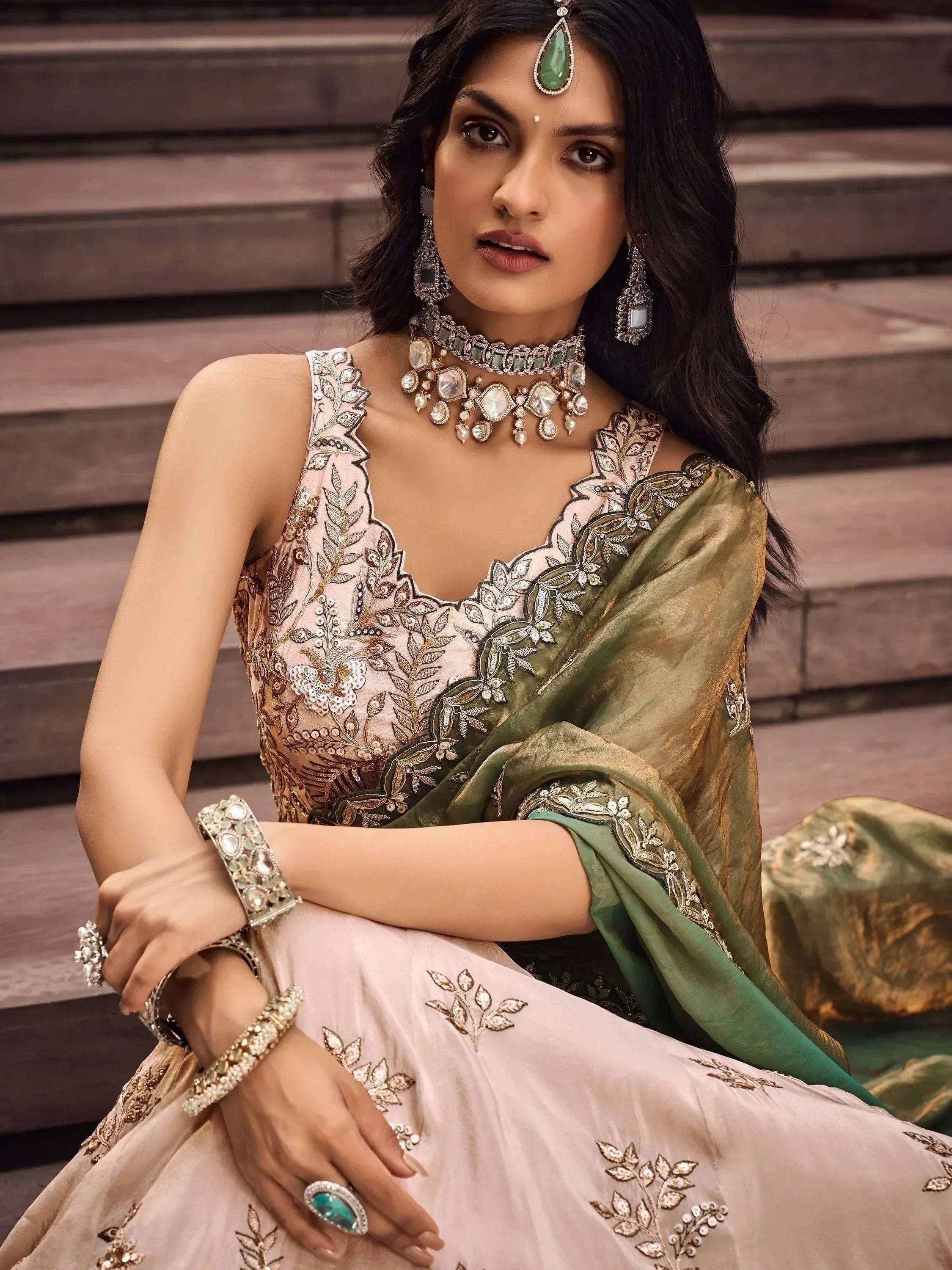 Elegant Indian ethnic wear with embroidered lehenga choli, green dupatta, and traditional jewelry for festive occasions.