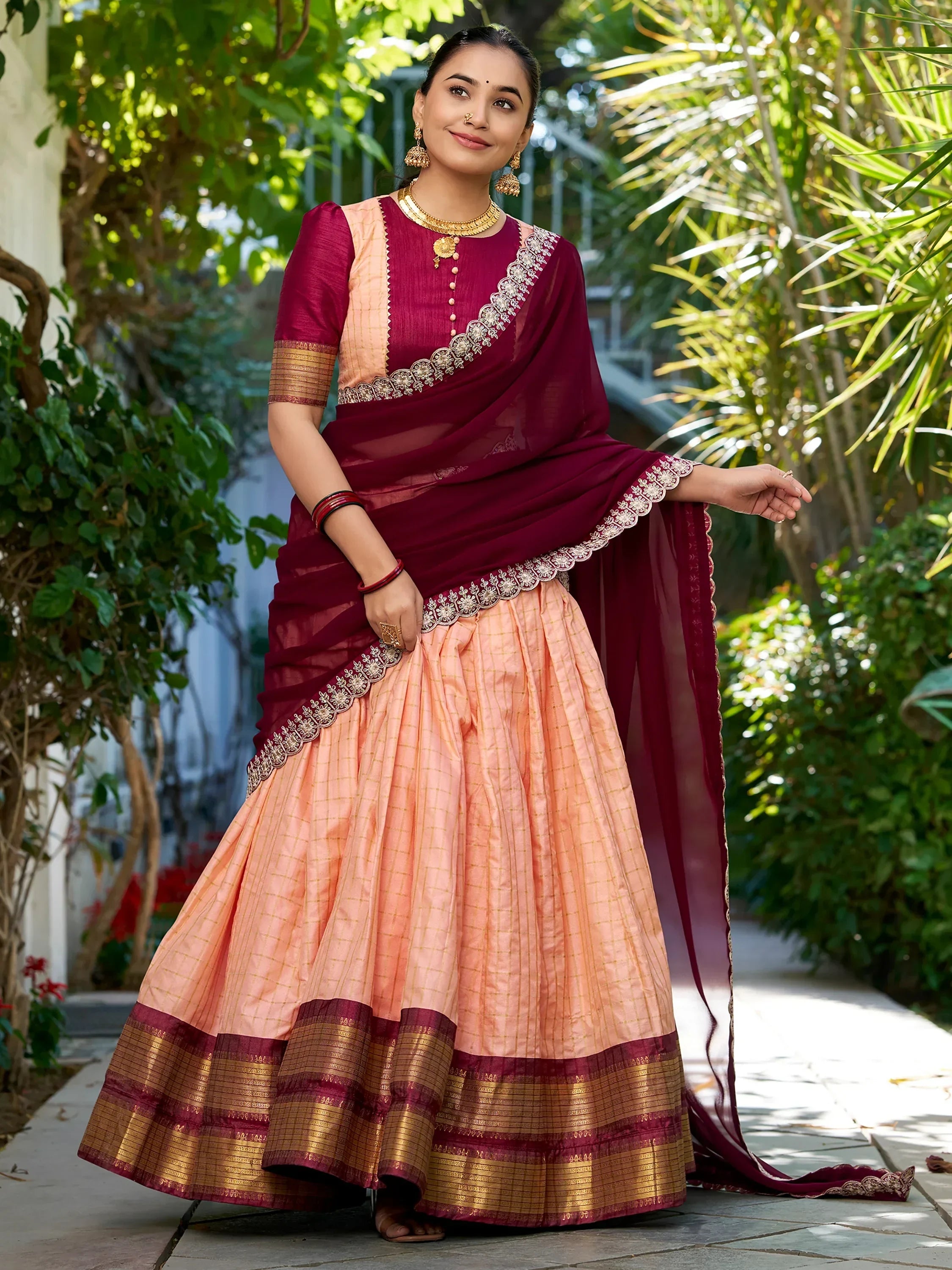 Elegant maroon and peach lehenga choli with intricate embroidery and gold border, perfect for festive occasions.