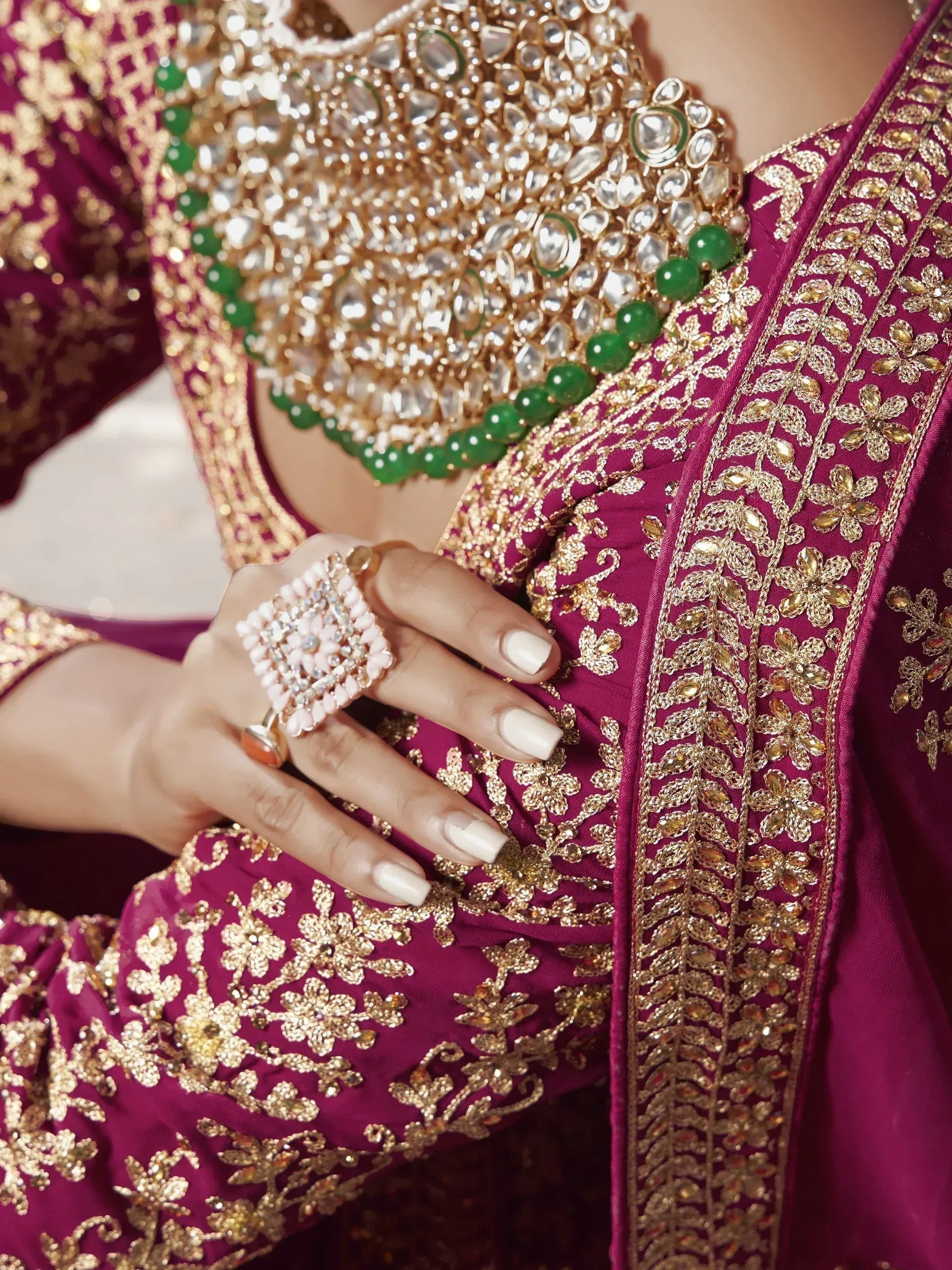 Luxury maroon lehenga choli with gold embroidery and green stone detailing, perfect for Indian weddings.