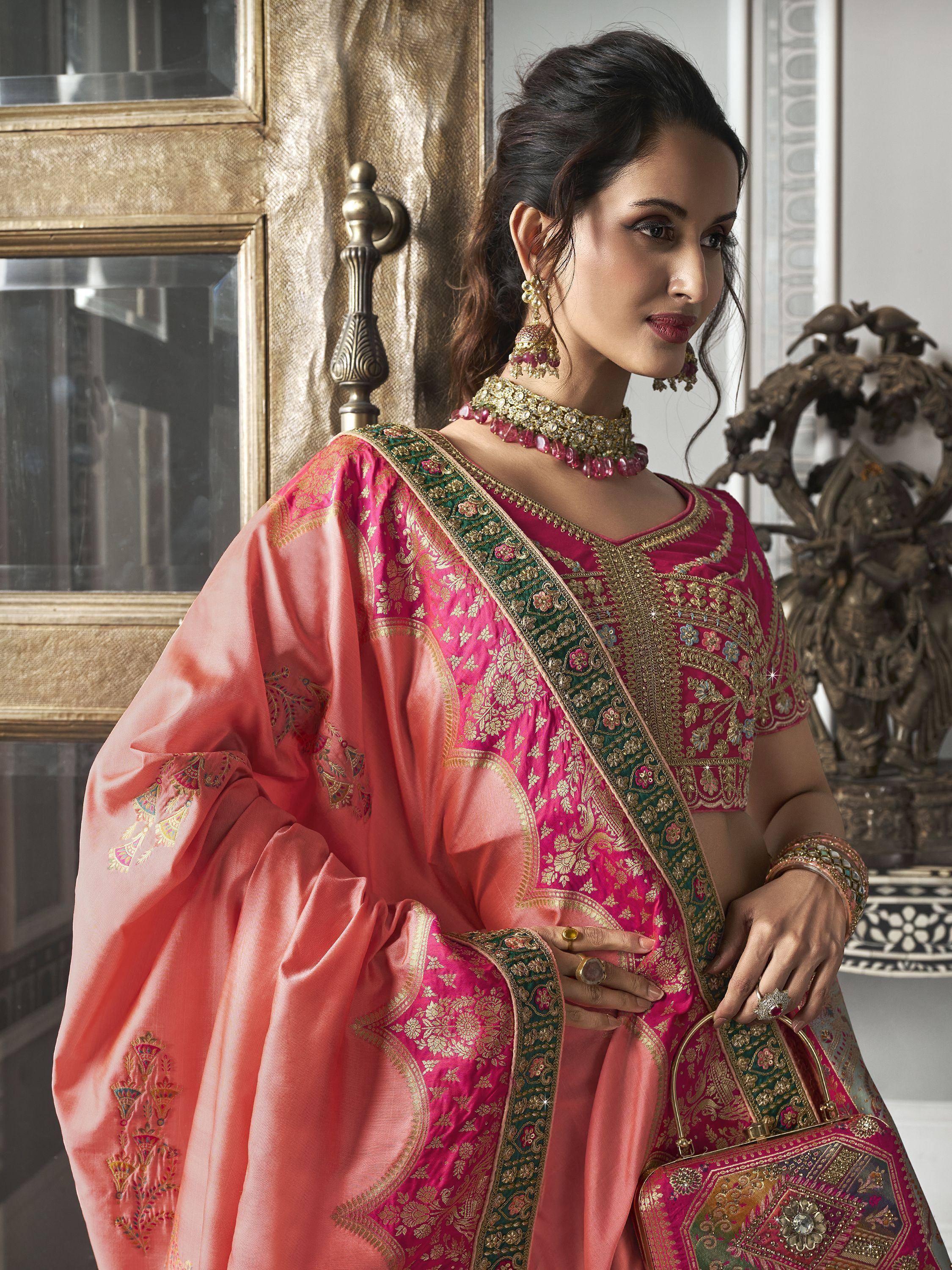 Woman in pink and peach embroidered Indian ethnic wear with gold detailing and matching jewelry