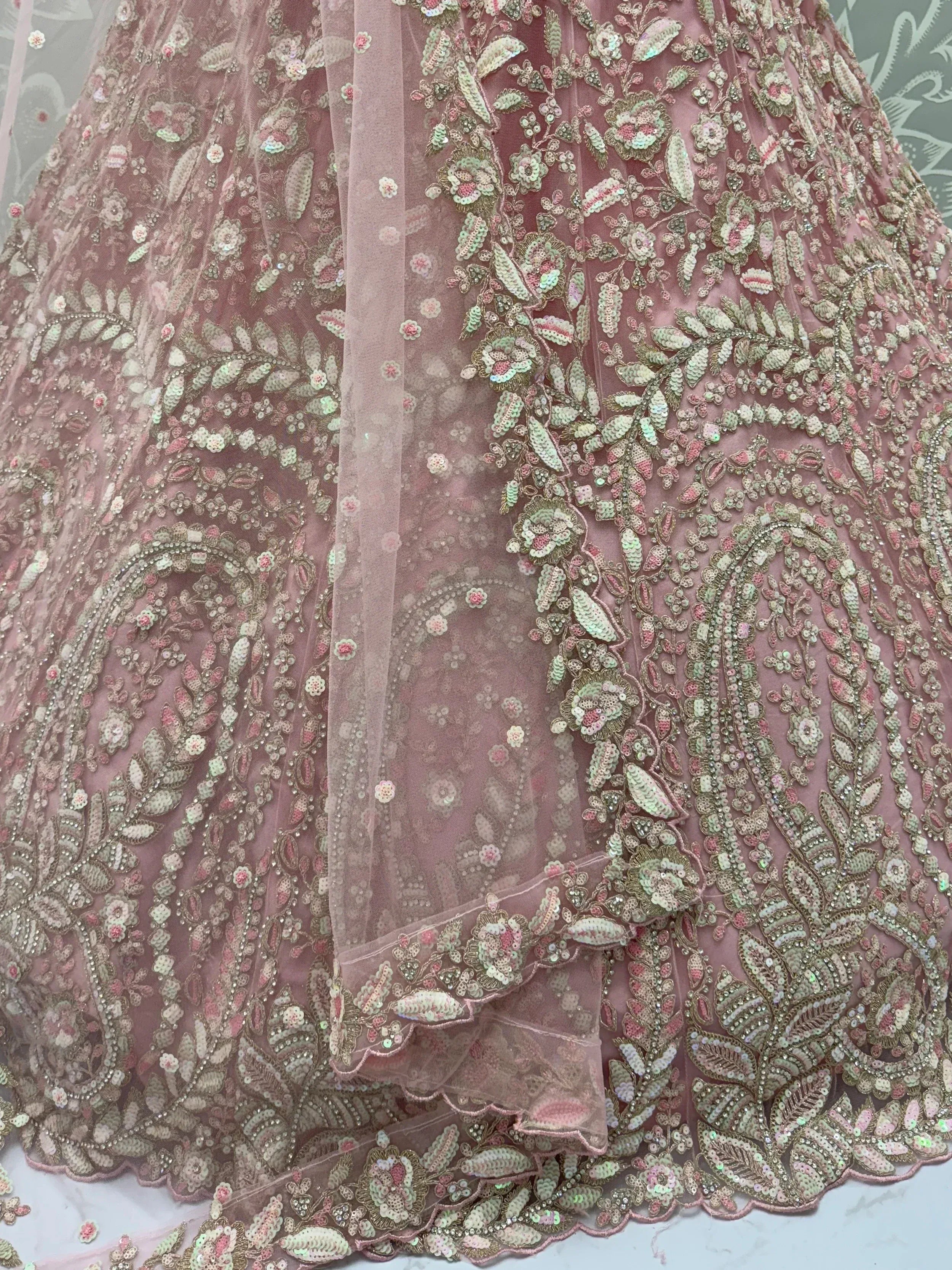 Dusty pink lehenga with intricate floral sequin embroidery and sheer overlay, perfect for Indian weddings or festive occasions.