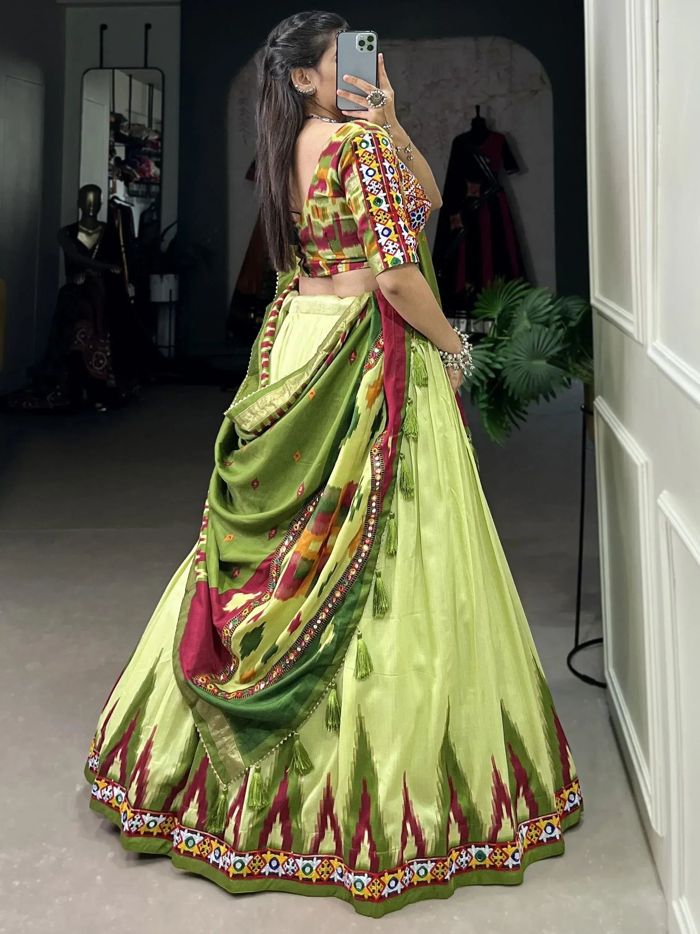 Woman in vibrant green and red ethnic lehenga choli with mirror work, perfect for Indian weddings and festive occasions.