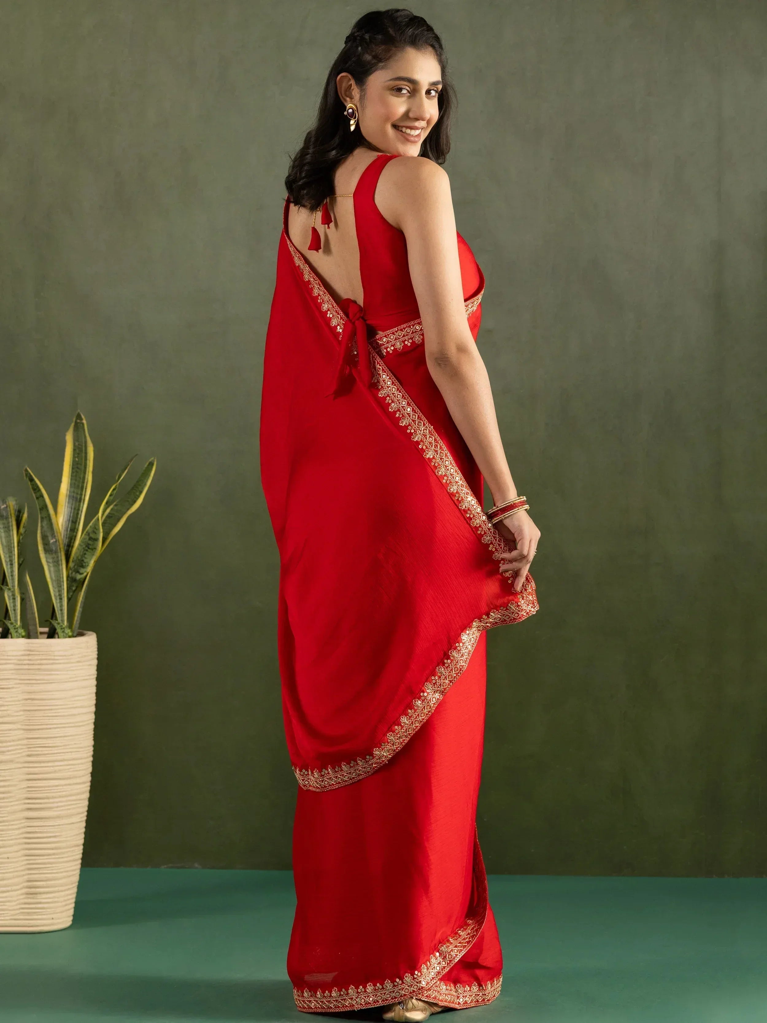 Red saree with gold embroidery and back tie, styled with ethnic jewelry for festive occasions