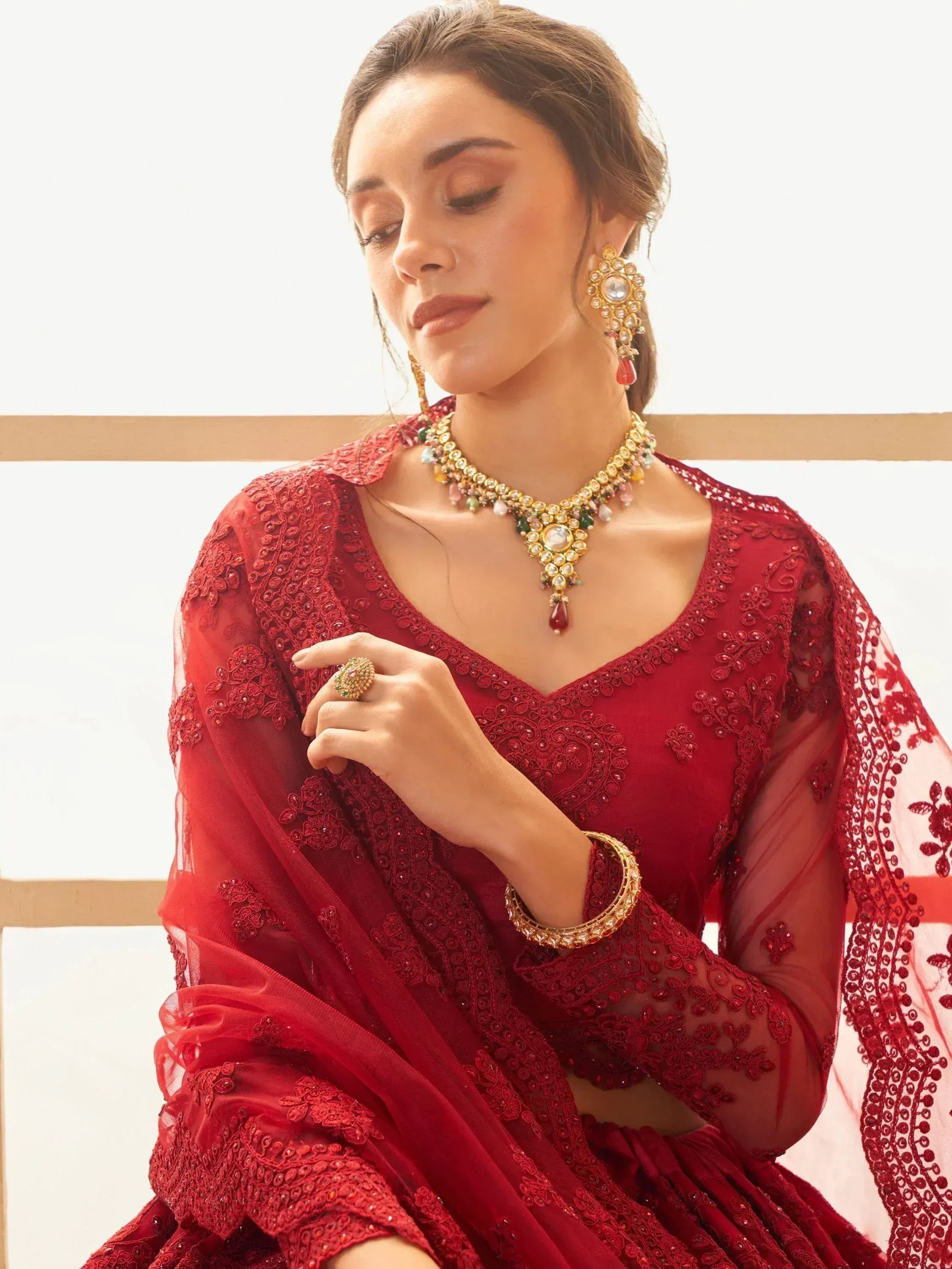 Elegant red embroidered lehenga choli with gold jewelry, perfect for Indian ethnic wear occasions