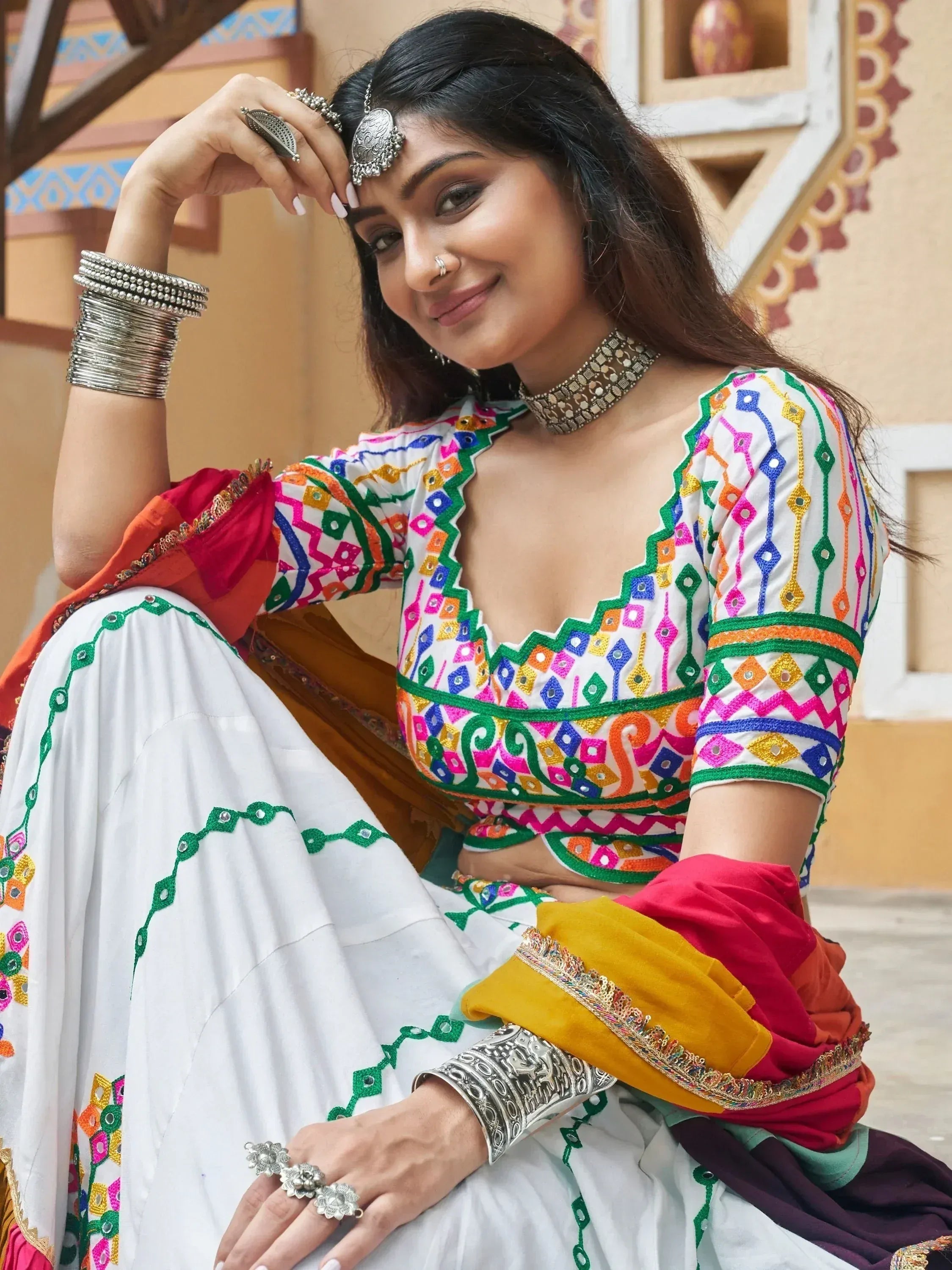 Woman in colorful embroidered Indian ethnic wear with mirror work, traditional jewelry, and vibrant dupatta