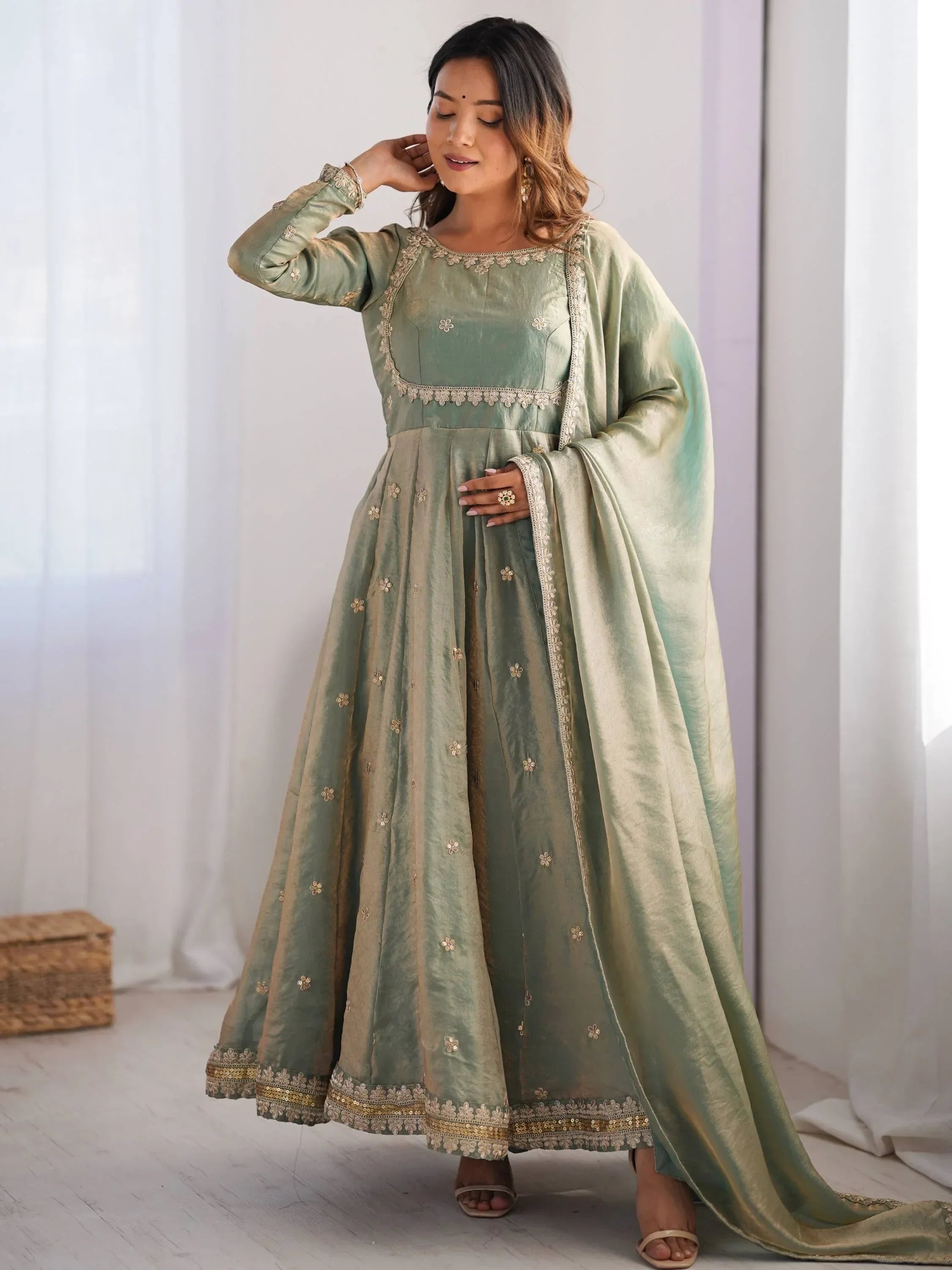 Woman wearing elegant green ethnic gown with gold embroidery and dupatta in bright room