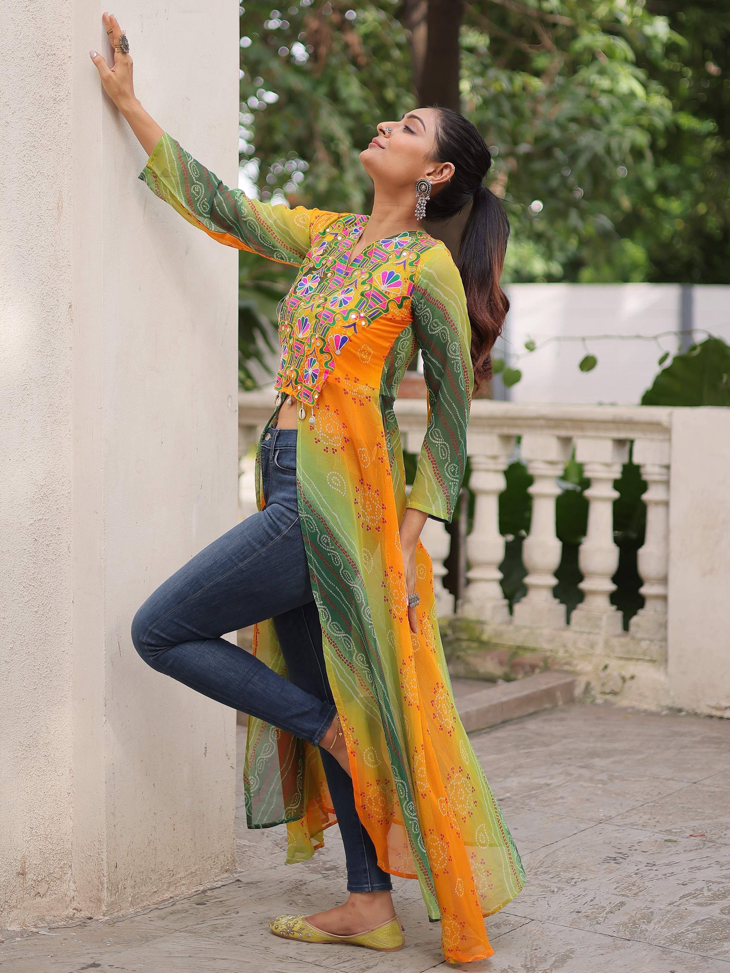 Vibrant orange and green embroidered ethnic kurti with sheer sleeves, paired with jeans and juttis