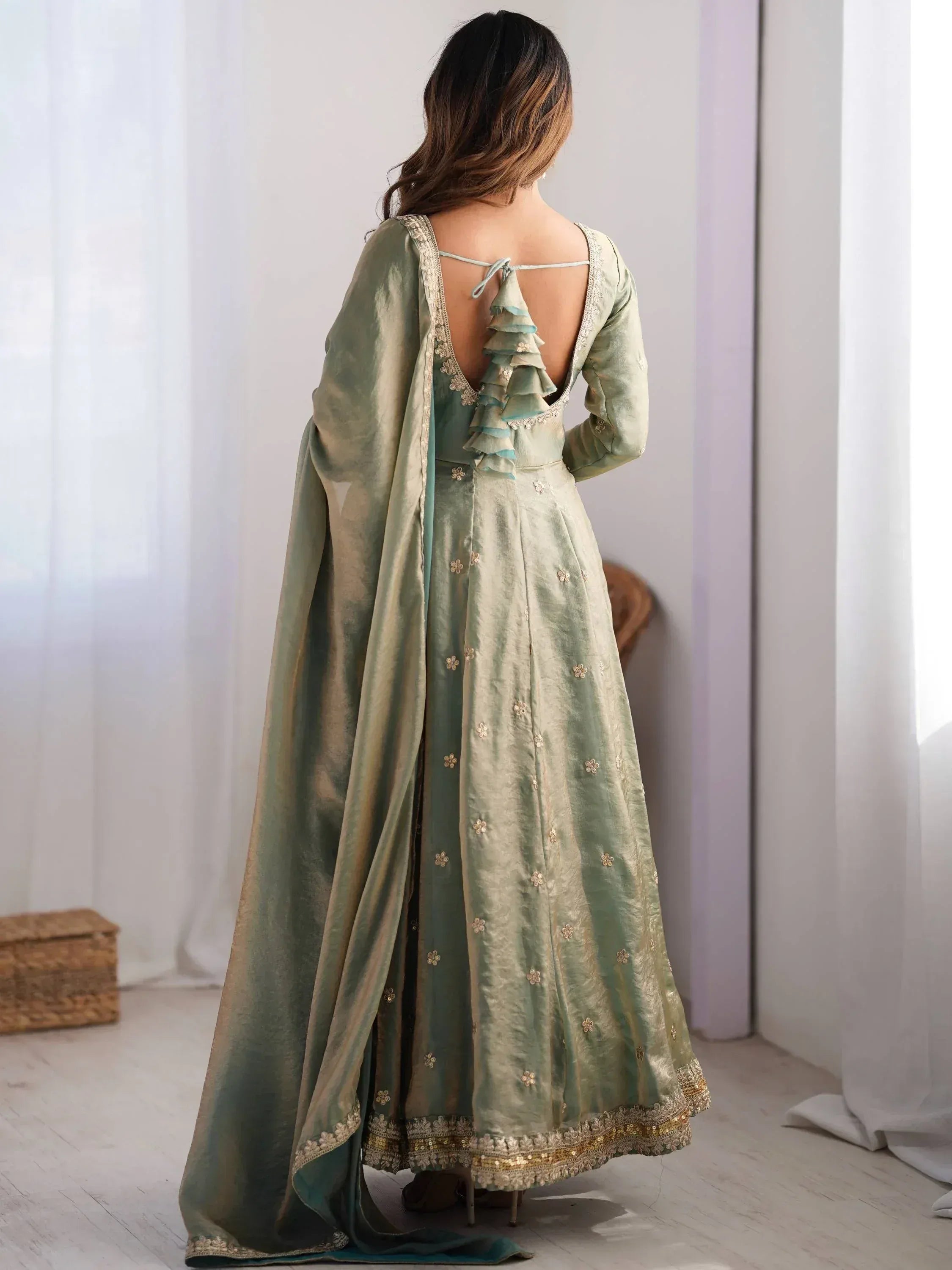 Woman in pastel green embroidered ethnic gown with dupatta, back design detail, indoor setting