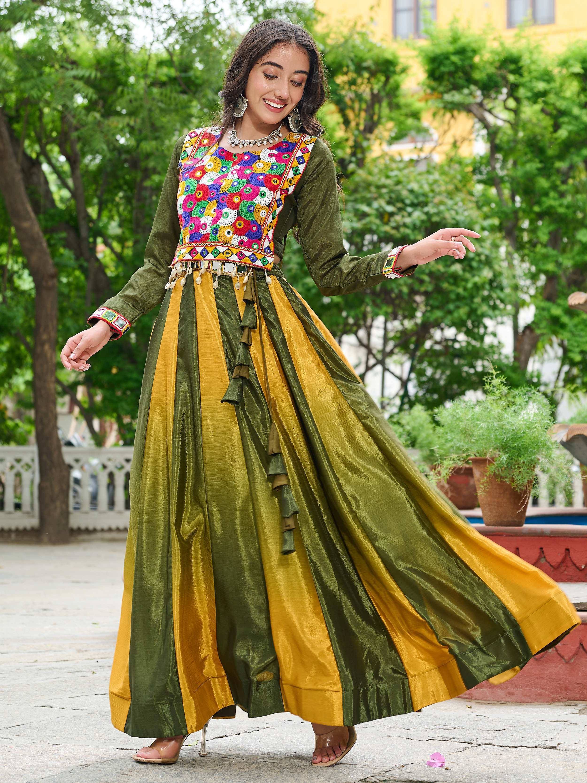 Woman in vibrant green and gold ethnic gown with colorful mirror work, perfect for Indian celebrations.