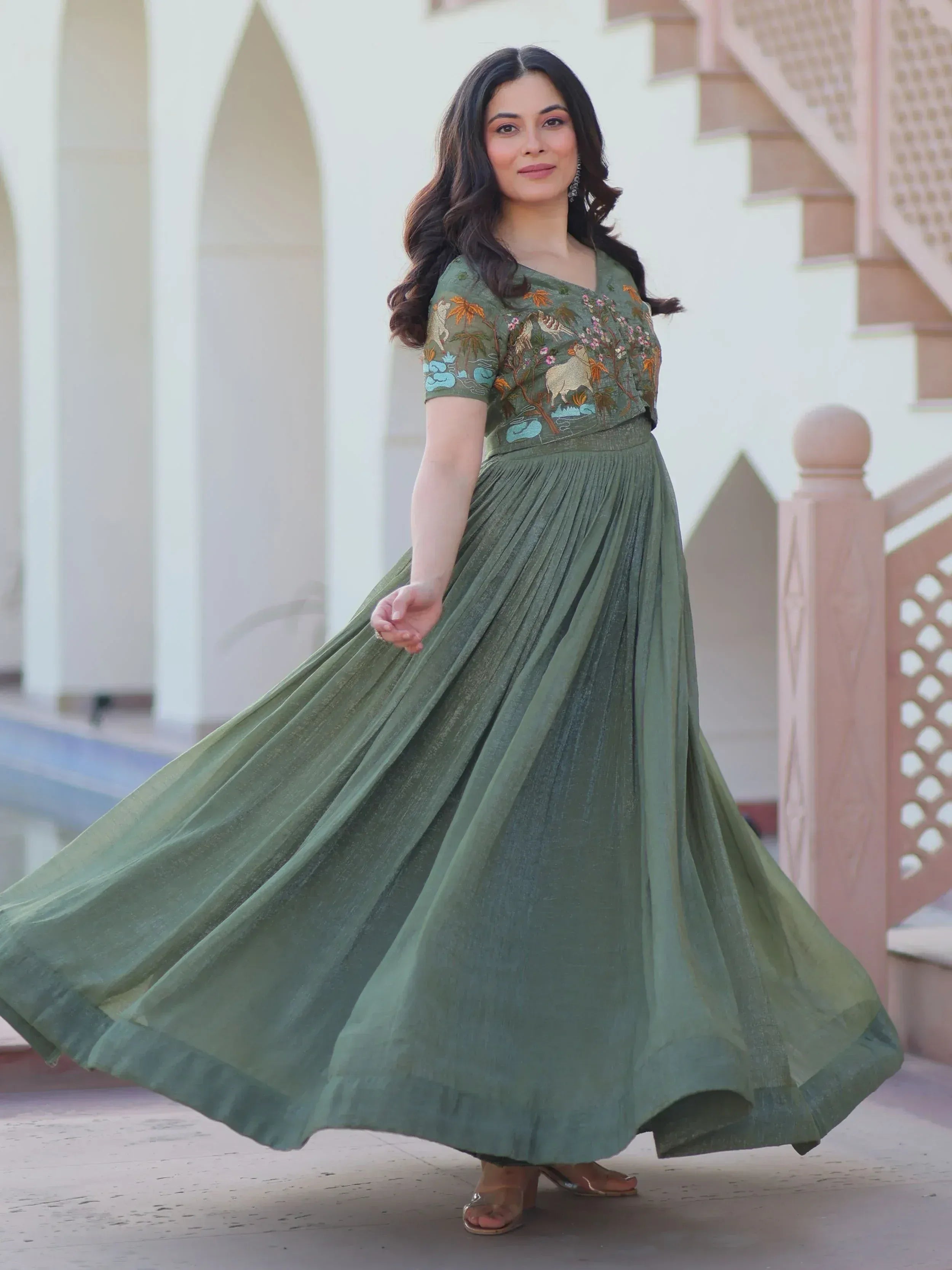 Woman in olive green embroidered ethnic gown with pleated skirt, perfect for Indian occasions