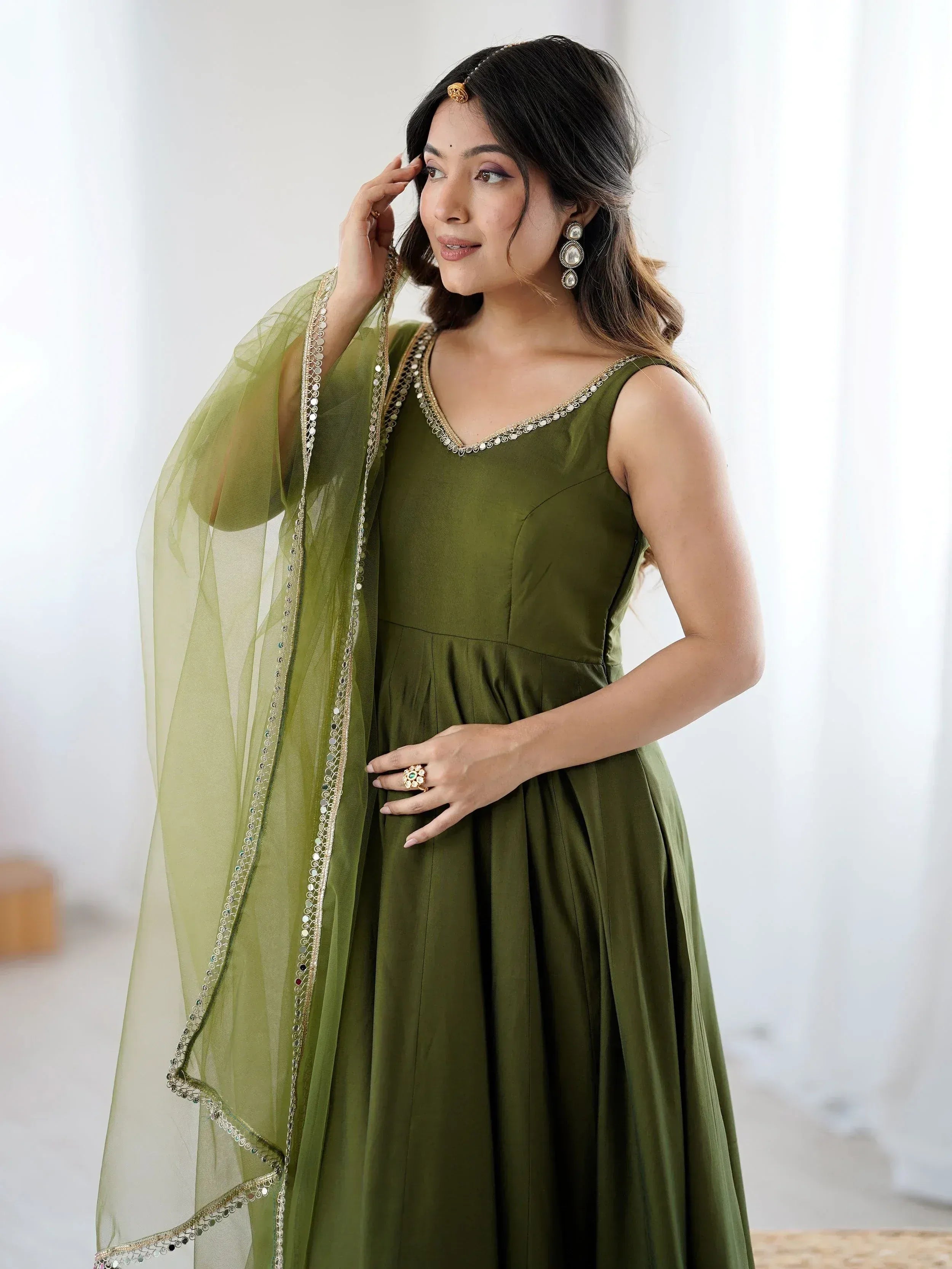 Olive green ethnic gown with gold embroidery and sheer dupatta, perfect for Indian weddings and parties.
