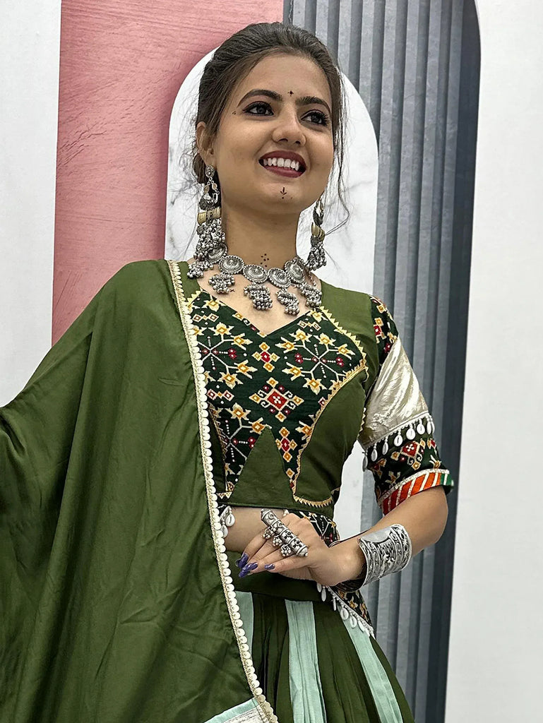Woman in olive green embroidered ethnic wear with silver jewelry, perfect for Indian festive occasions.