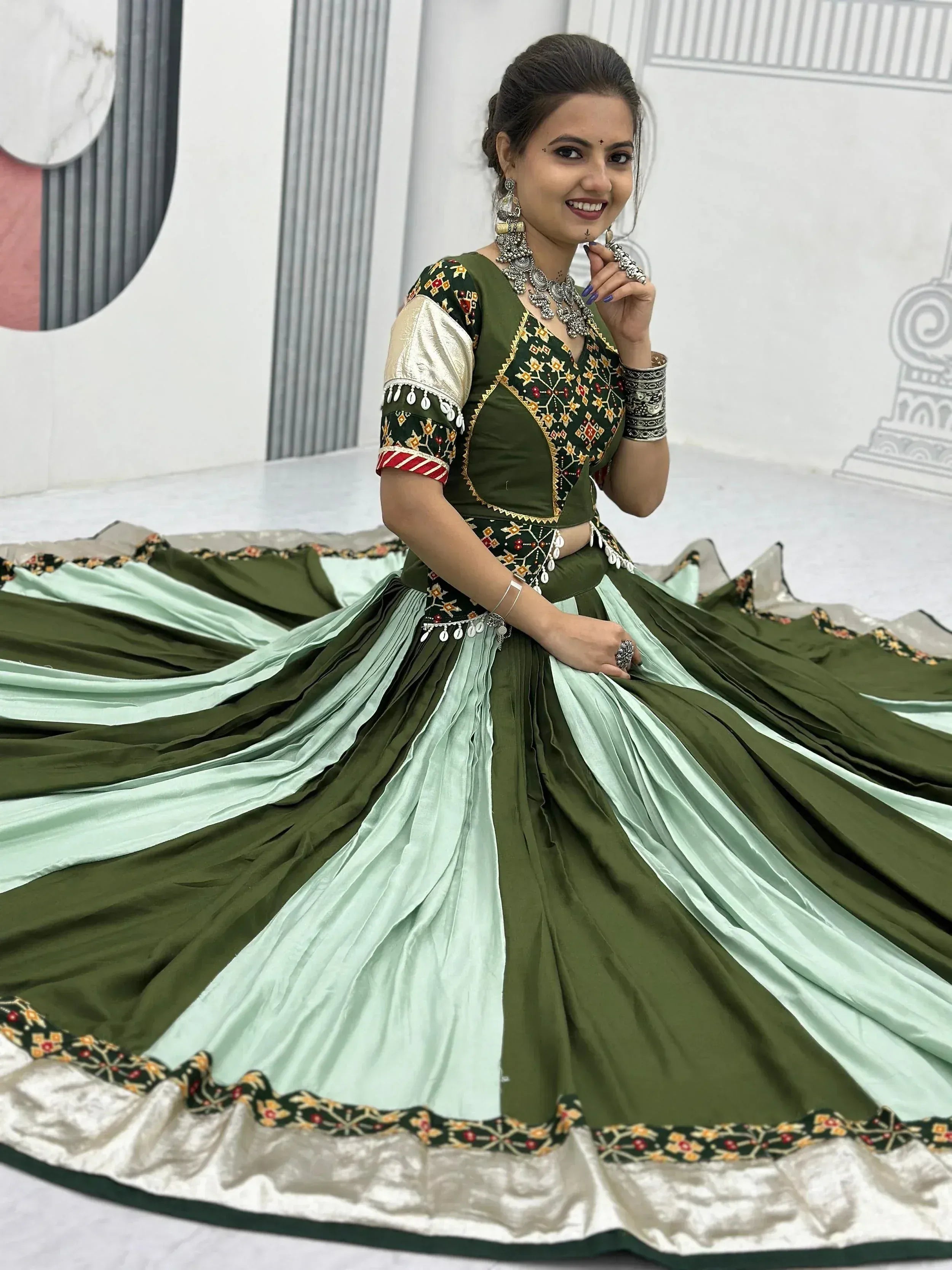 Woman in olive green and mint lehenga choli with intricate embroidery and traditional jewelry