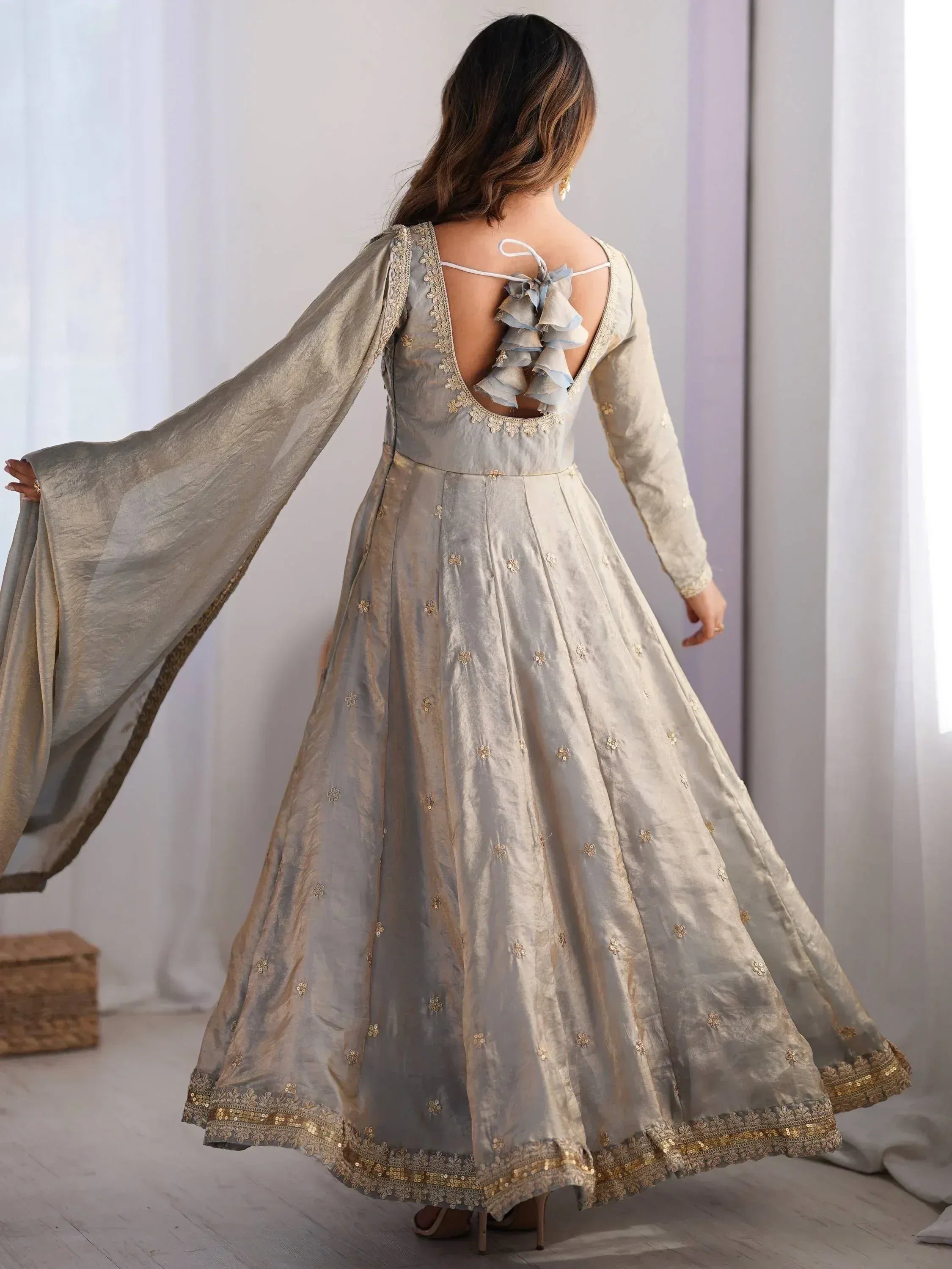 Woman in a grey ethnic gown with gold embroidery and open back design