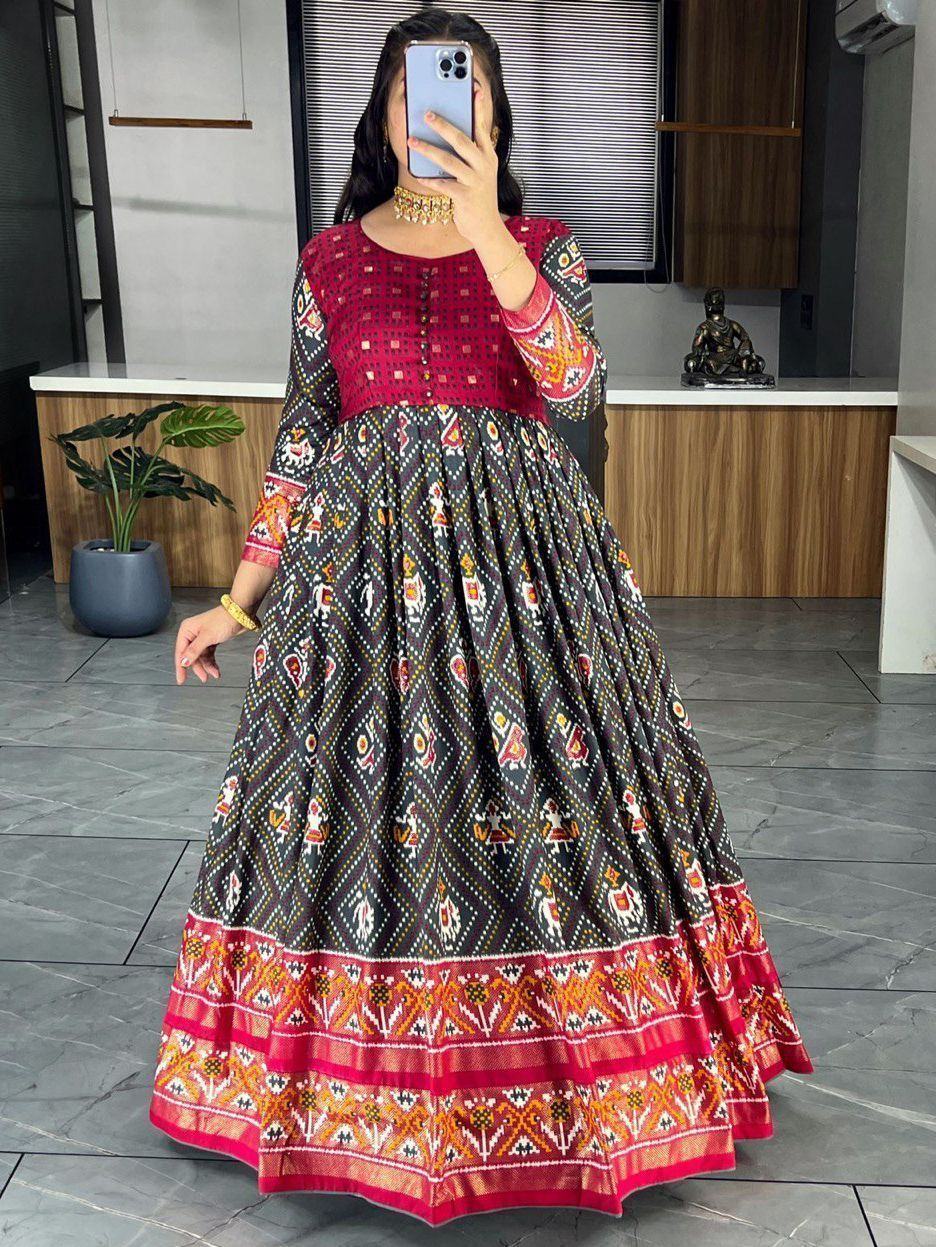Woman wearing a black and red printed ethnic gown with traditional patterns, long sleeves, and flared skirt.