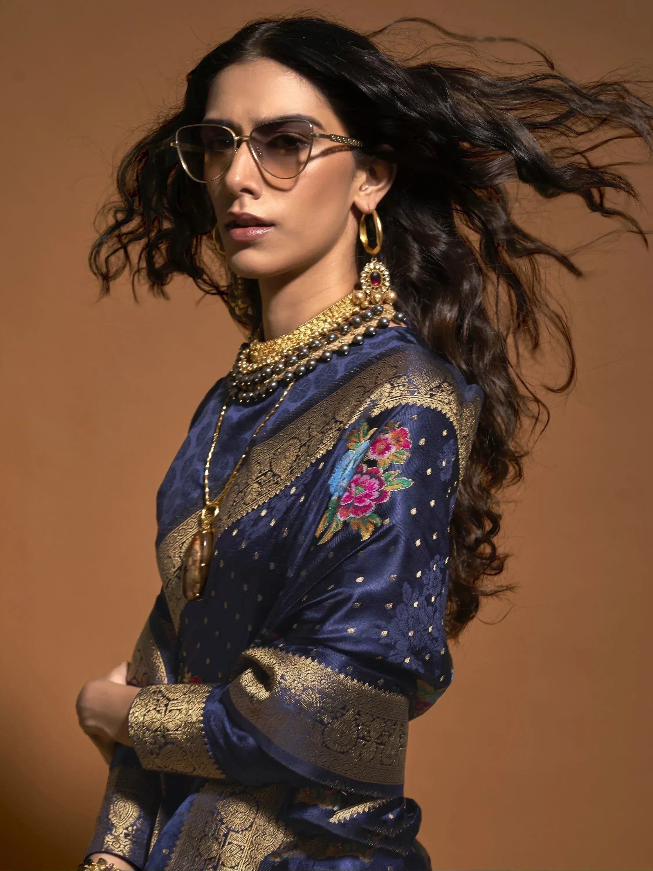 Woman in blue floral embroidered ethnic gown with gold detailing and statement jewelry