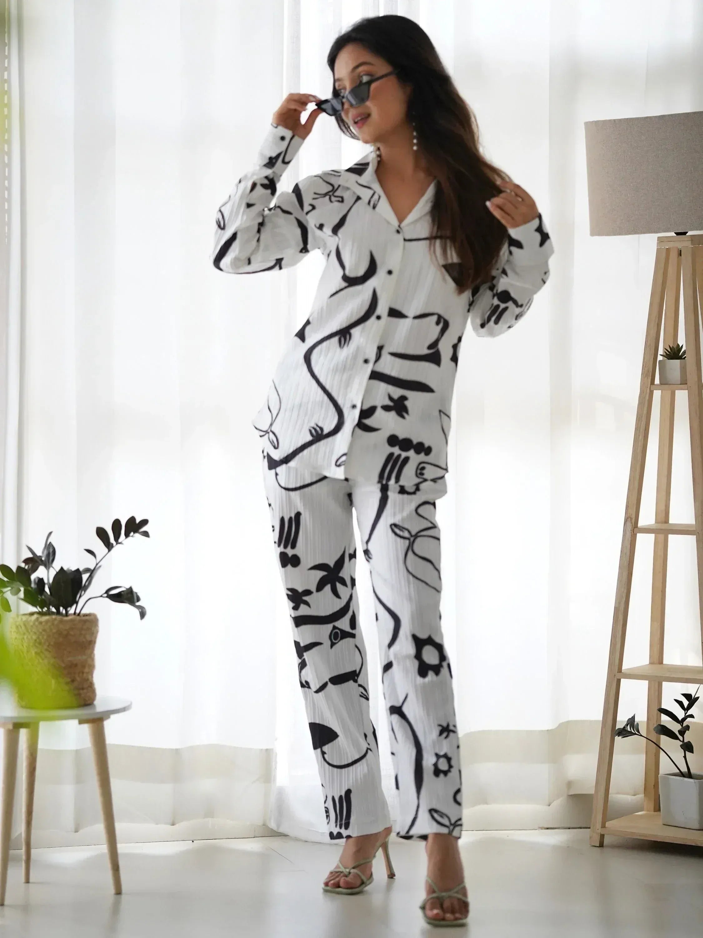 Woman in white black abstract print pajama set with long sleeves and wide legs, stylish home wear