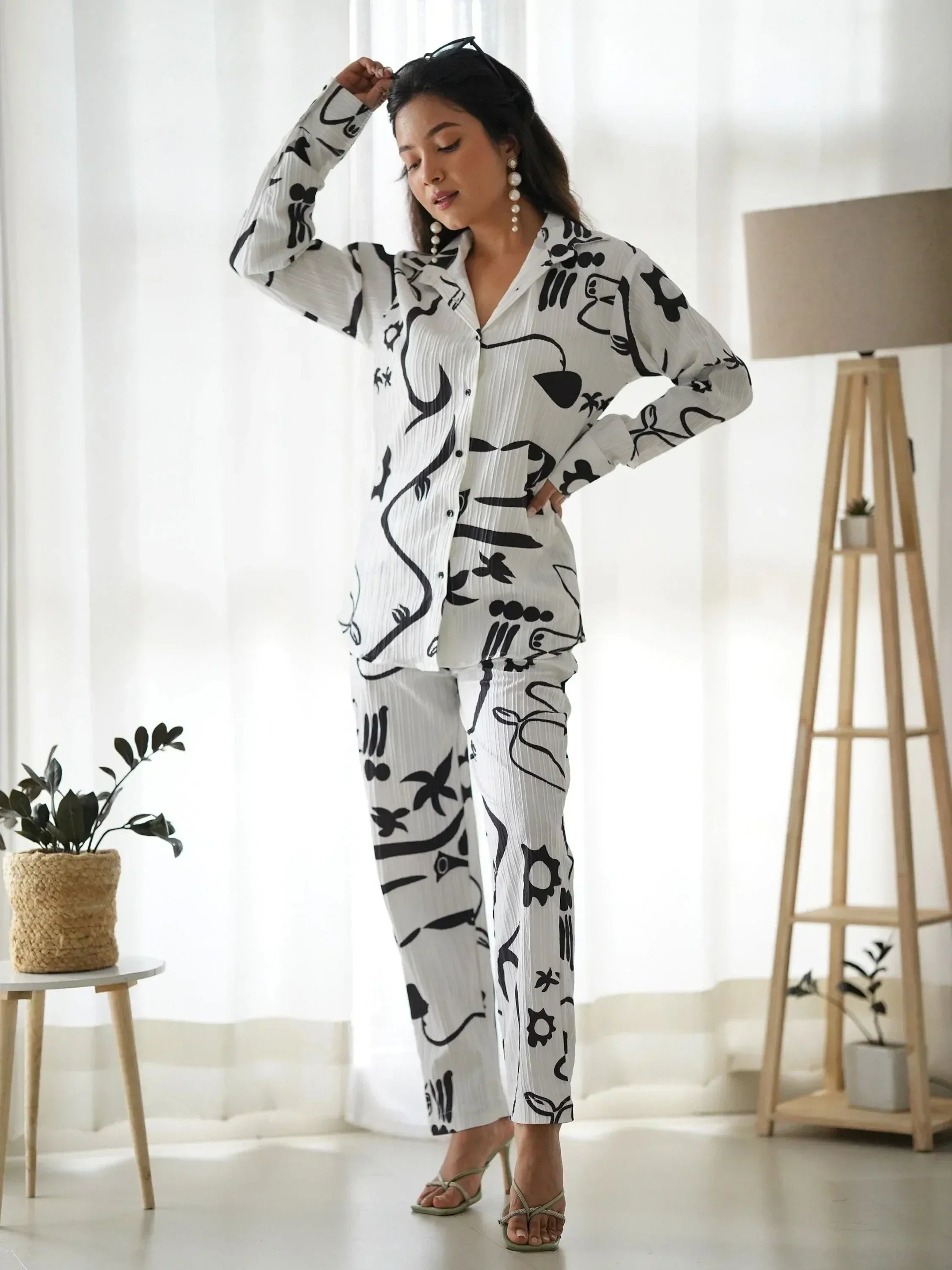 Woman in white and black abstract print ethnic palazzo set with button-down top, styled with heels and pearls
