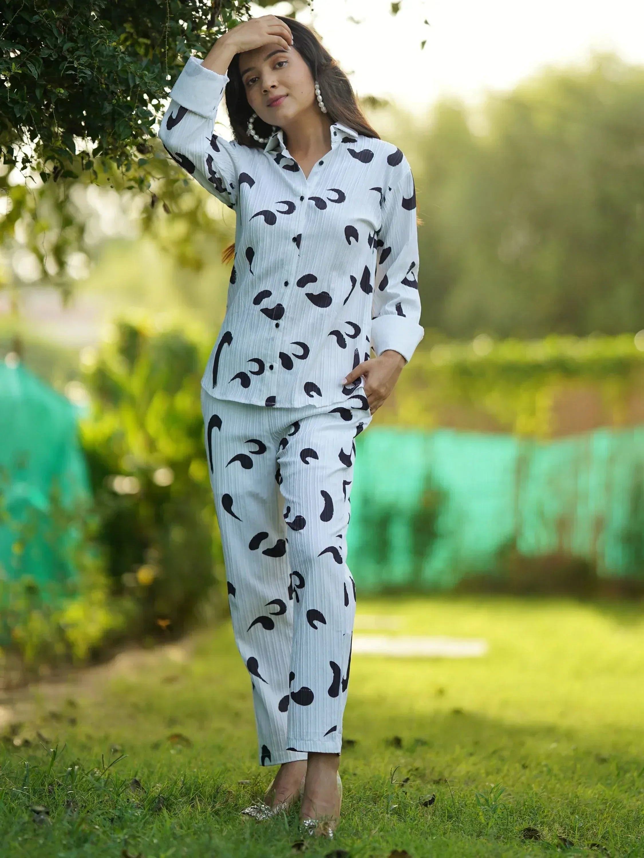 Woman in white and black printed ethnic kurta set with palazzo pants, standing outdoors in garden