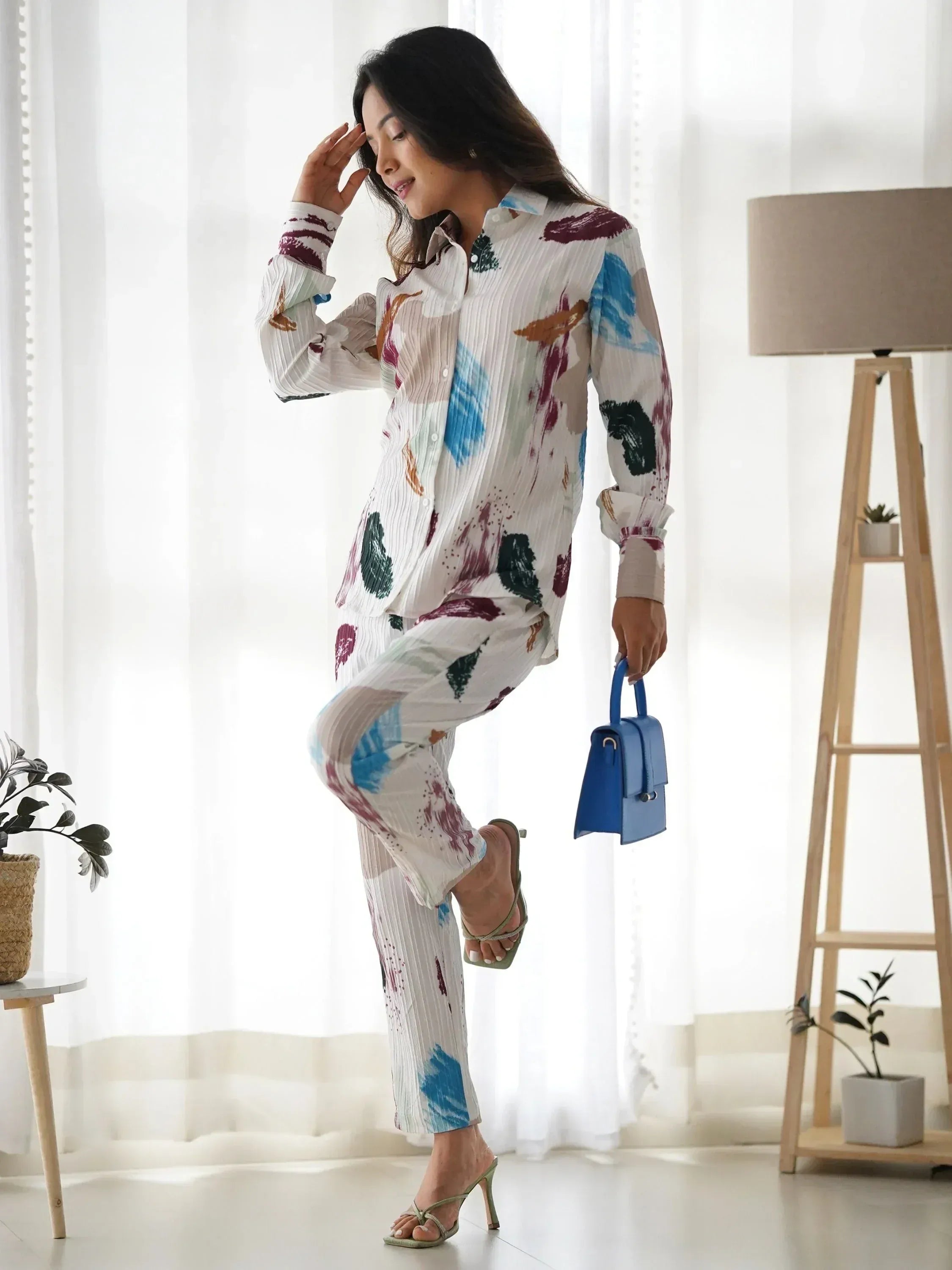 Woman in colorful printed ethnic shirt and pants with blue handbag, stylish Indian wear
