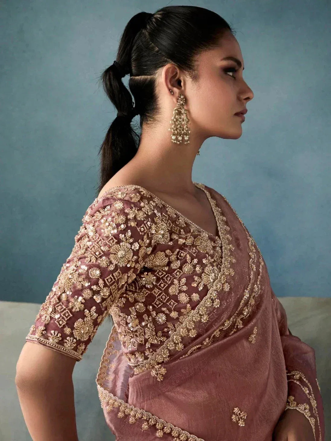 Elegant mauve saree with gold floral embroidery and matching blouse, styled with statement earrings.