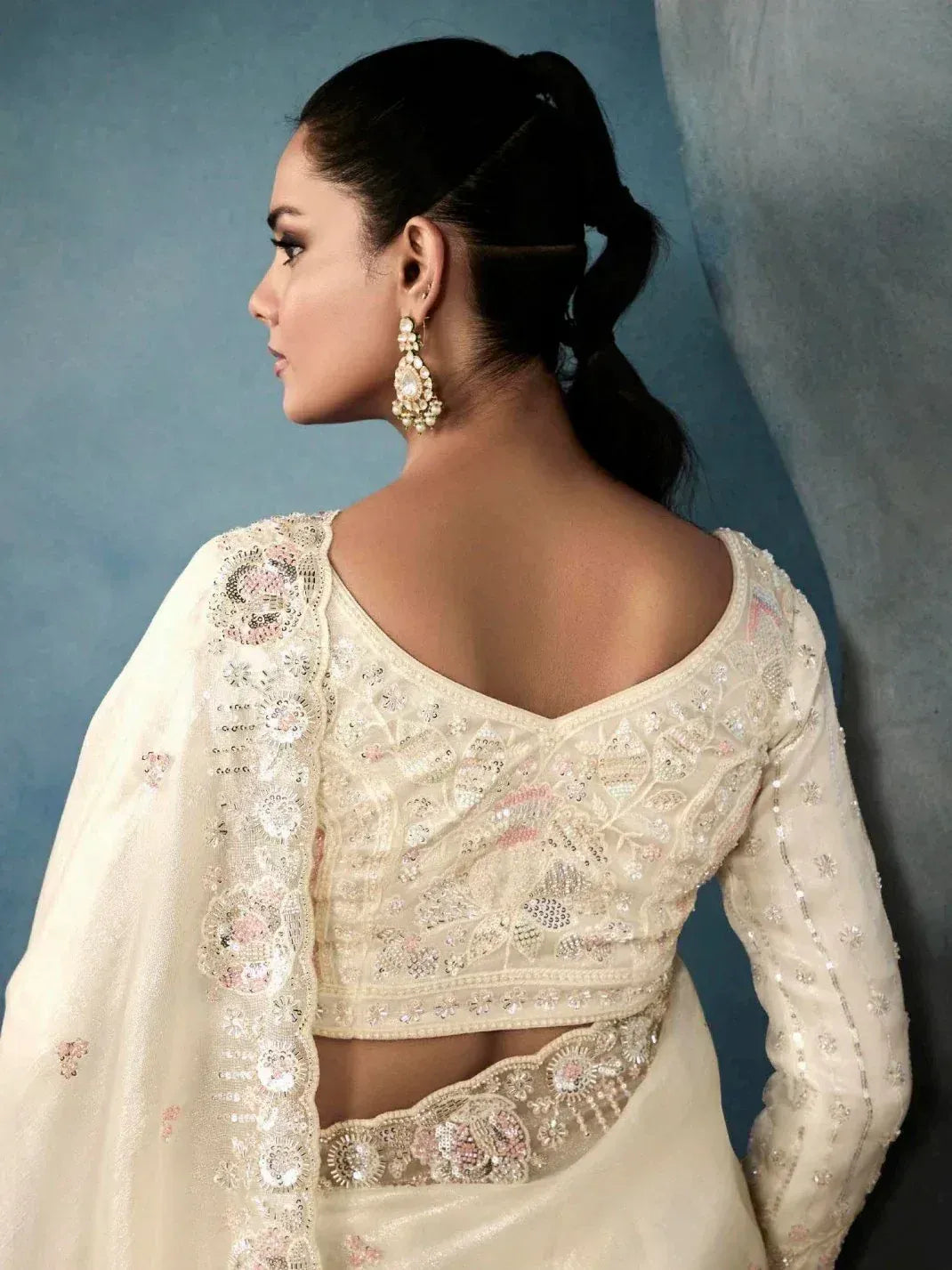Elegant cream embroidered lehenga choli with backless blouse and floral detailing, perfect for Indian ethnic wear.