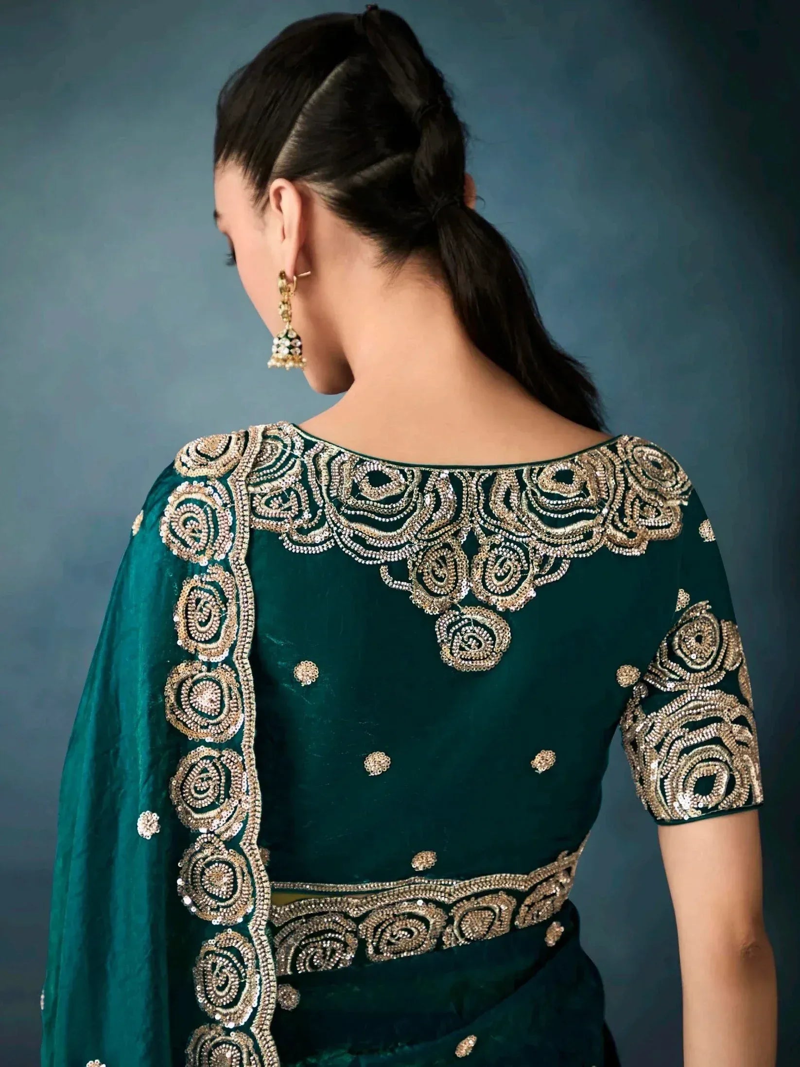 Emerald green velvet saree blouse with intricate gold floral embroidery and sequin detailing, perfect for Indian ethnic wear.