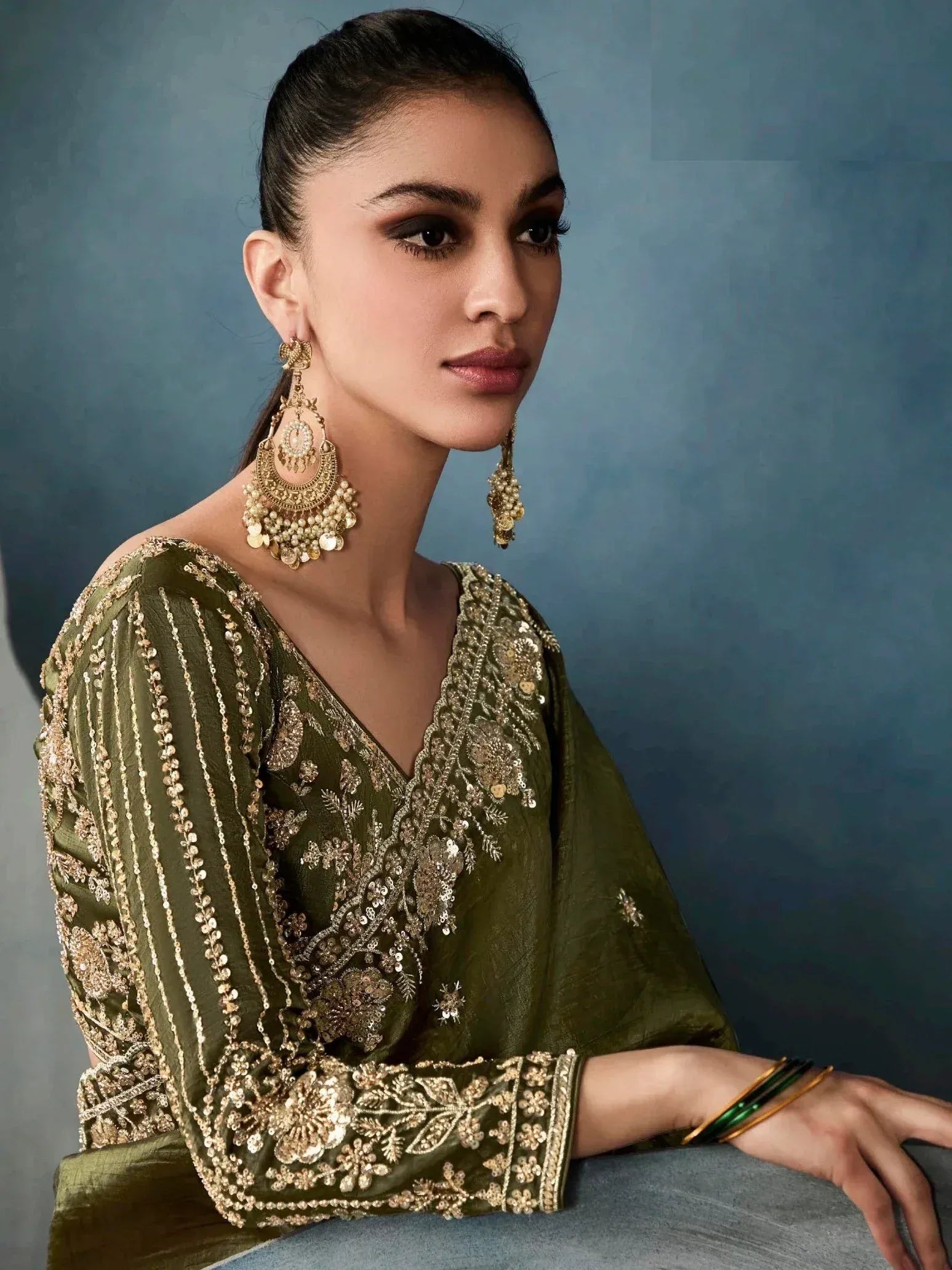 Olive green embroidered ethnic gown with gold detailing, paired with statement earrings and bangles.