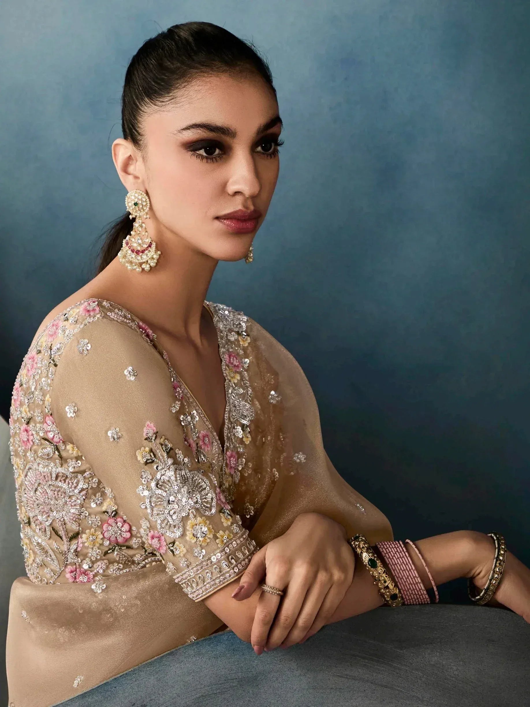 Woman in elegant beige floral embroidered ethnic gown with statement earrings and bangles