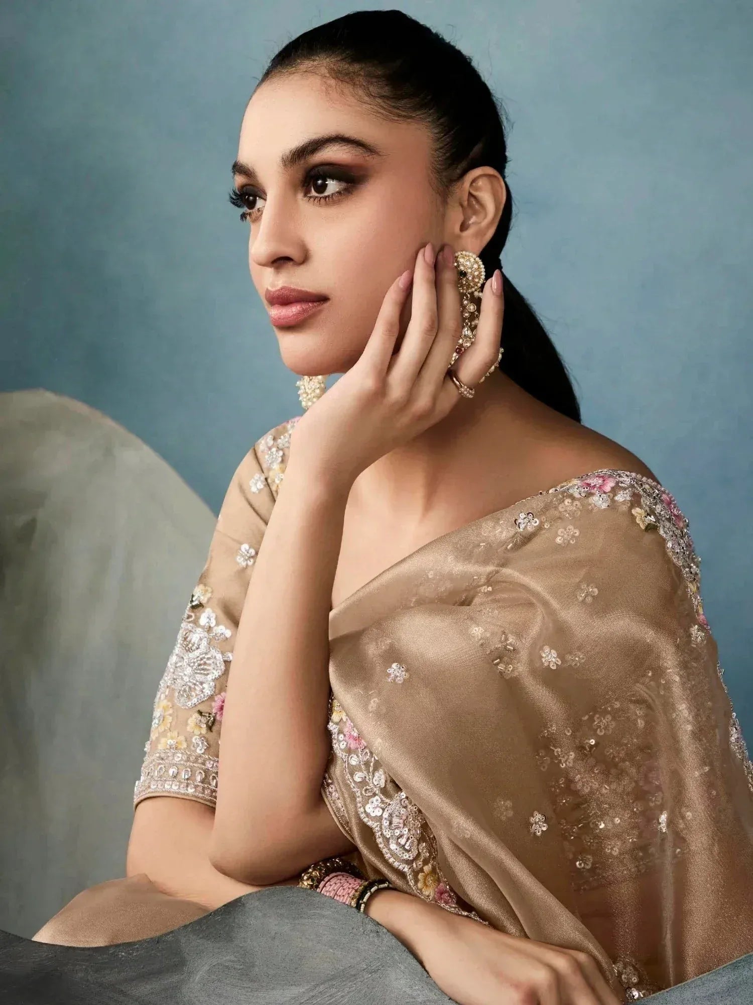 Elegant woman in designer ethnic gown with floral embroidery and statement jewelry, perfect for Indian occasions.
