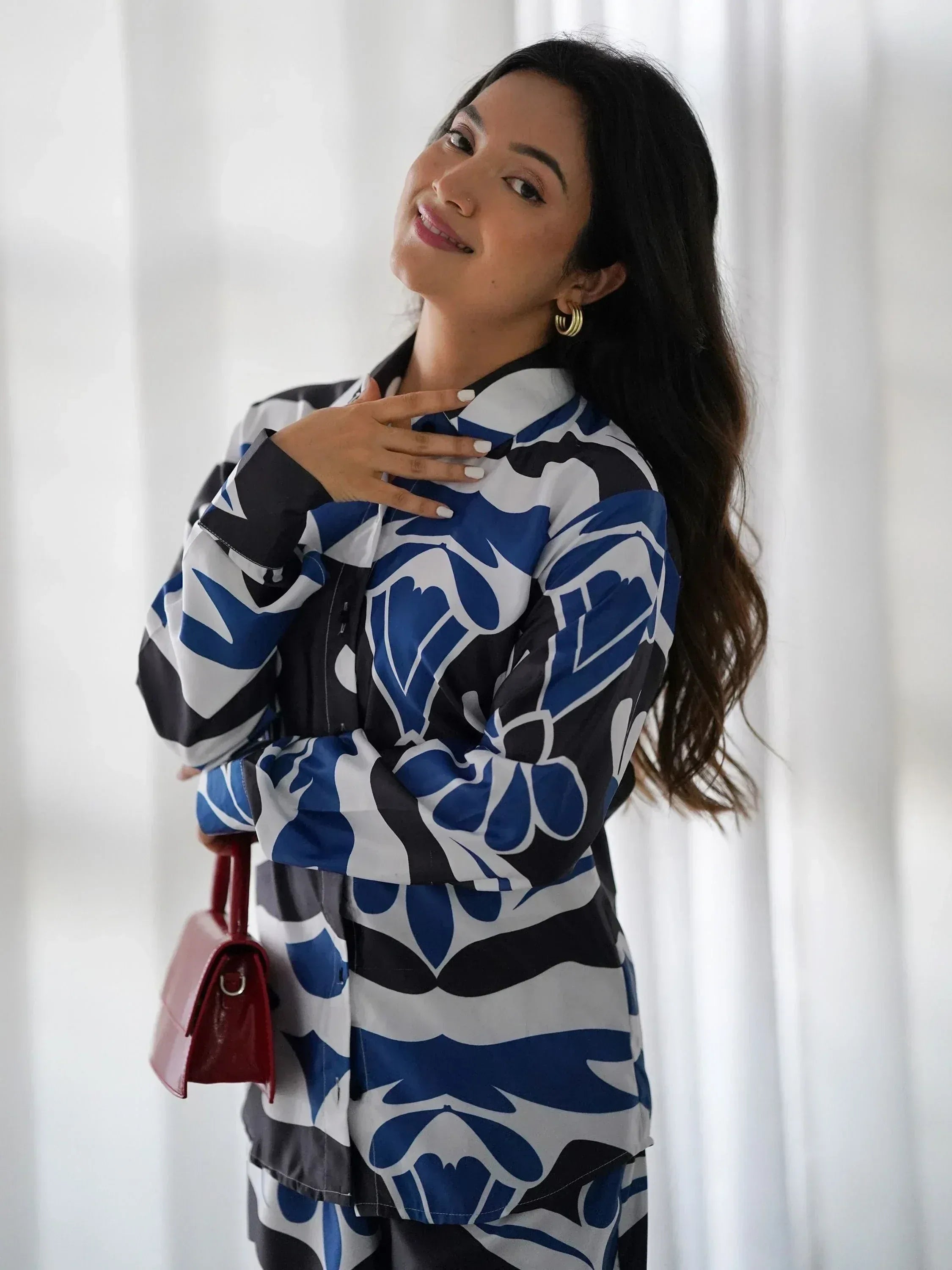 Woman in blue and white floral print ethnic kurta with red handbag, stylish Indian wear