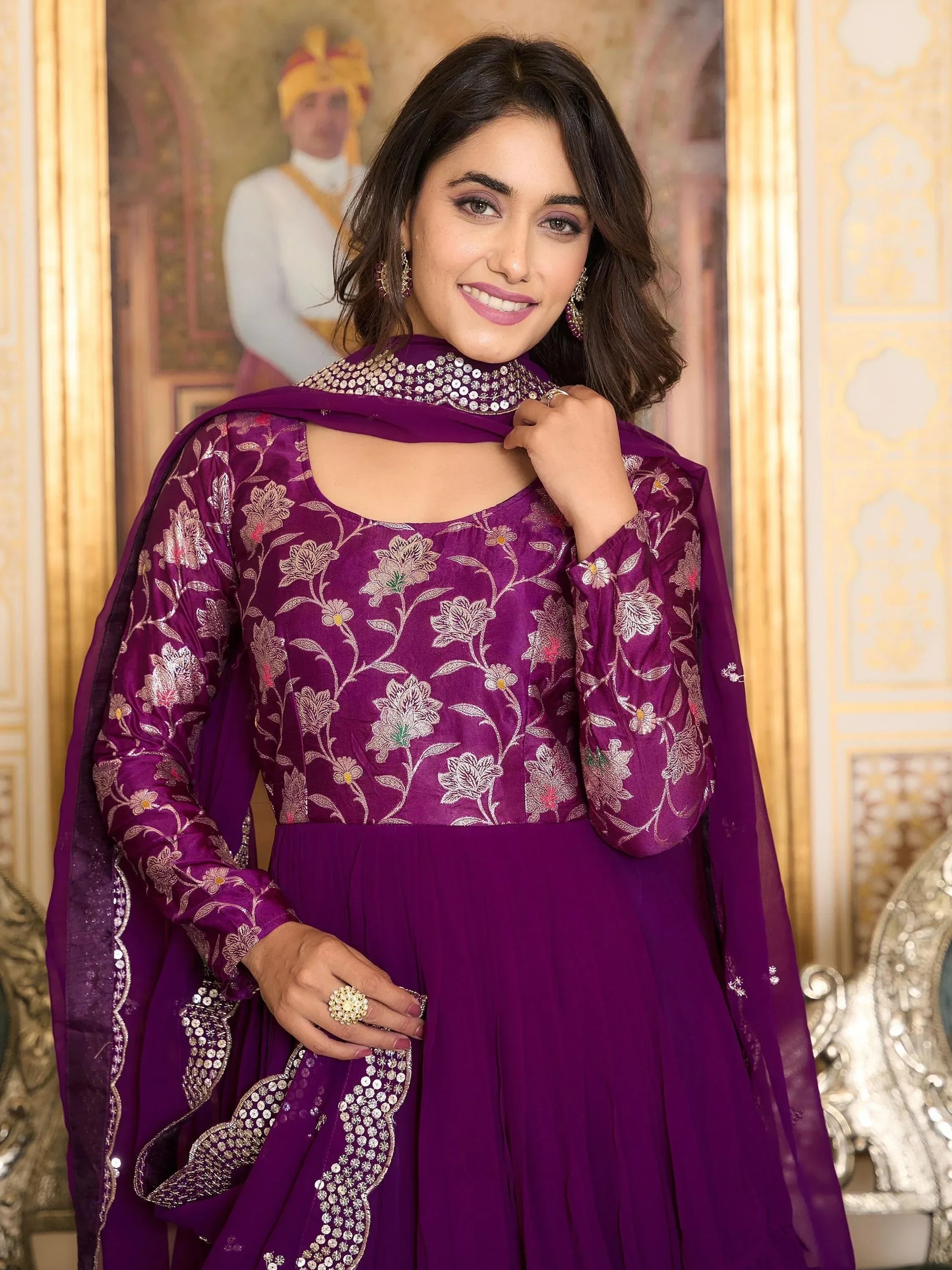 Woman in a purple embroidered ethnic gown with dupatta, posing indoors