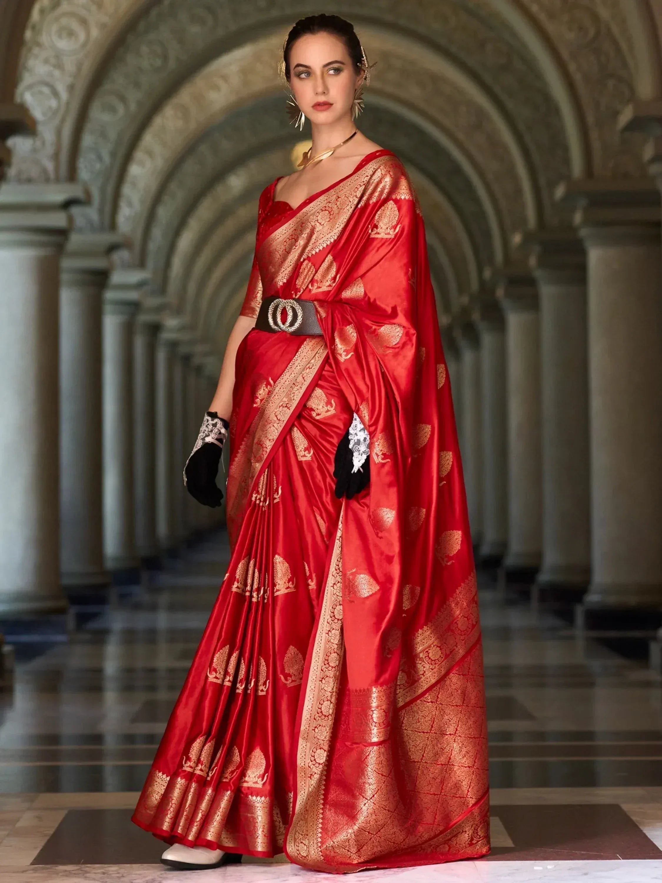 Red and gold designer saree with intricate embroidery, styled with black gloves and belt for ethnic wear