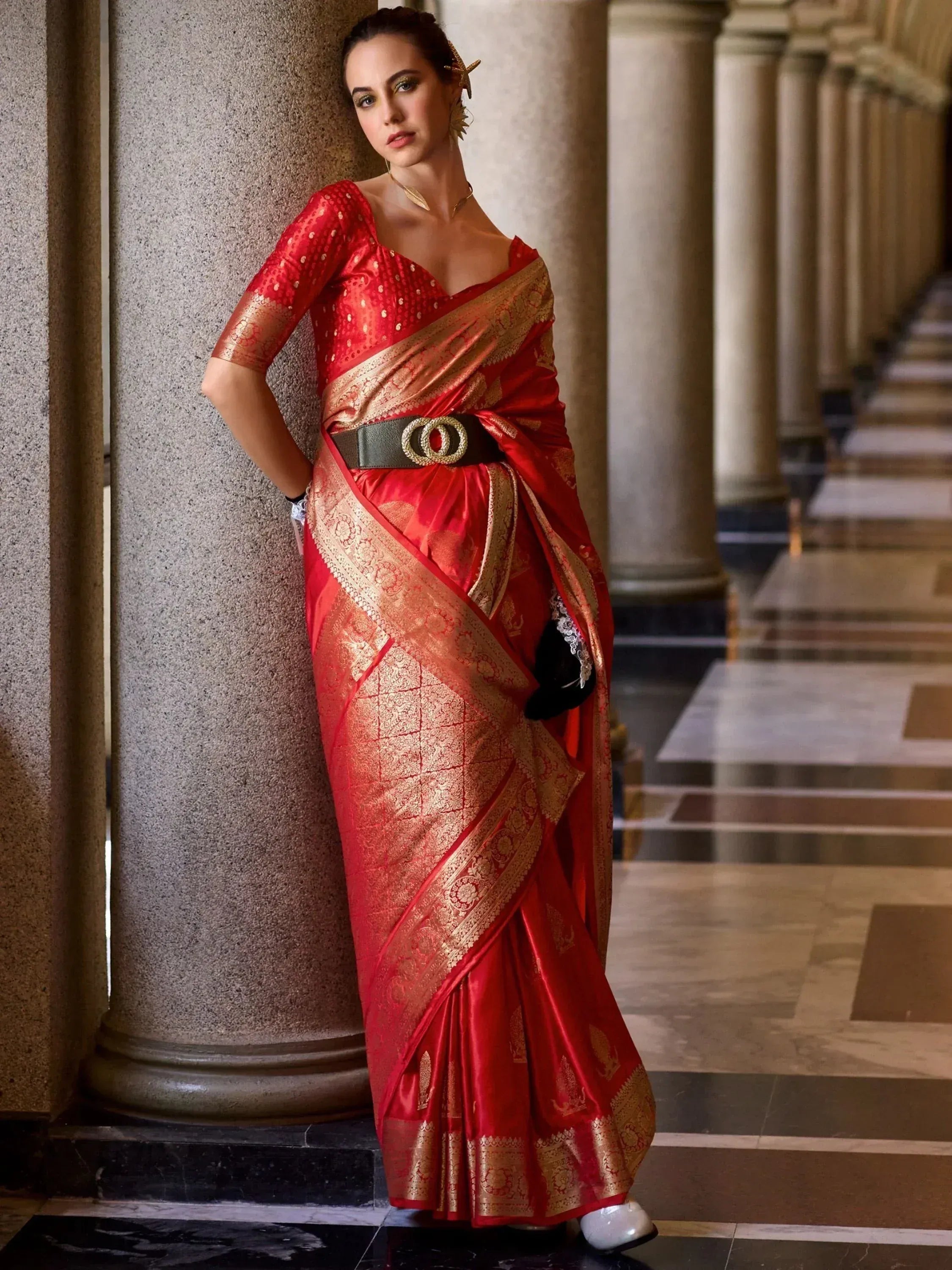 Red and gold designer saree with intricate embroidery, styled with a belt, perfect for ethnic occasions
