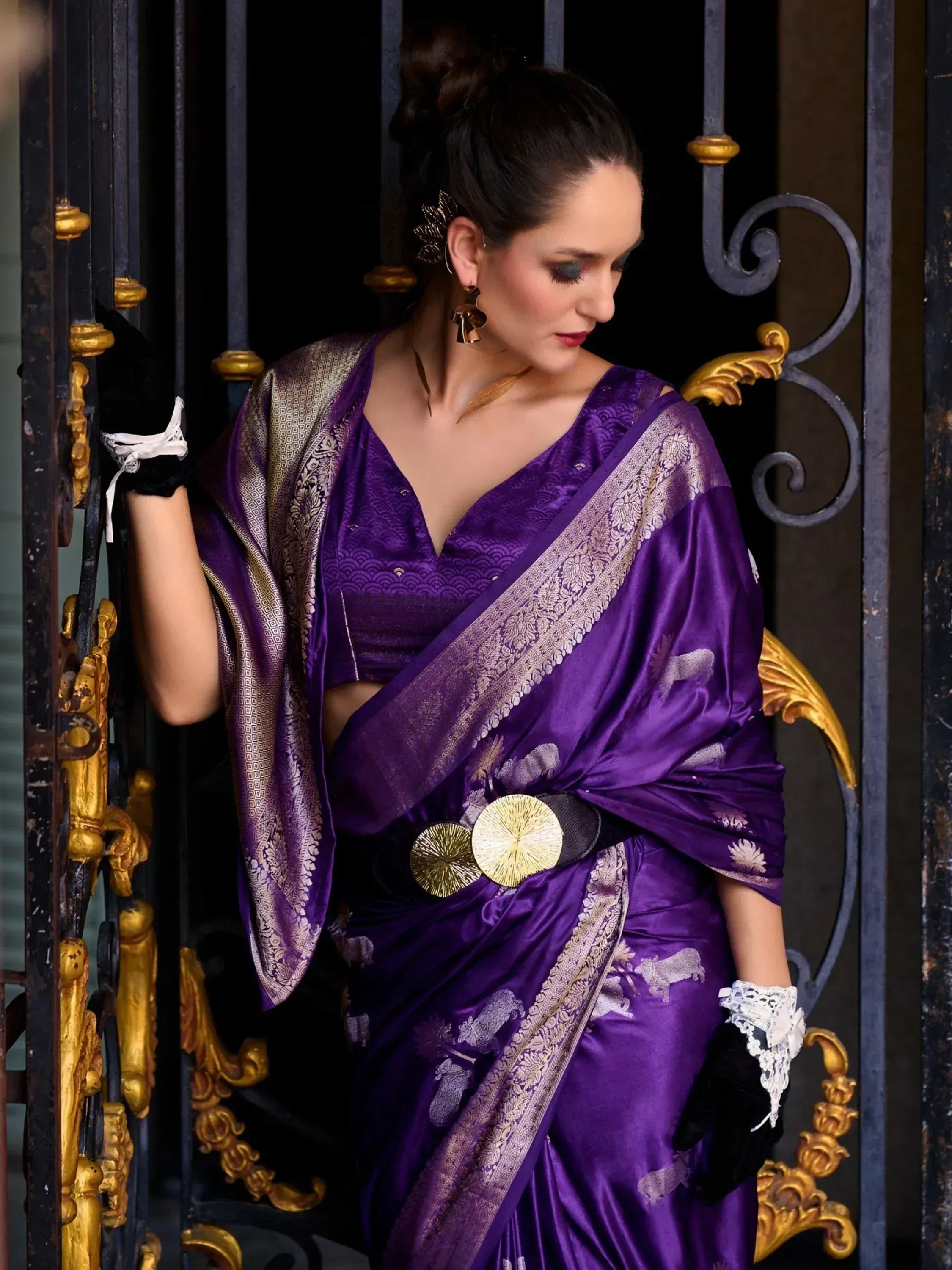 Purple designer saree with gold border and elephant print, styled with black gloves and belt for ethnic wear.
