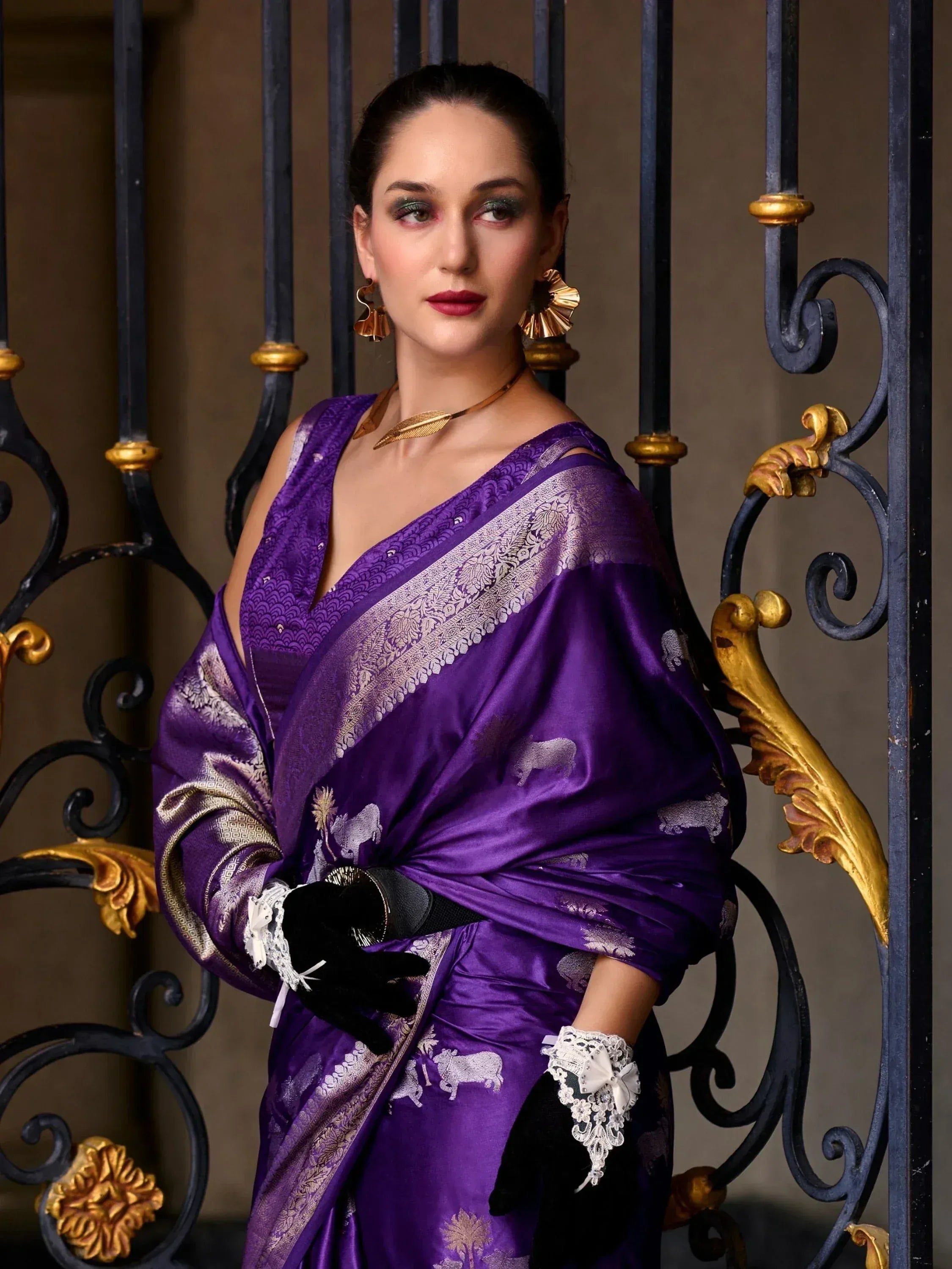 Elegant purple silk saree with gold elephant motifs, paired with black lace gloves and statement gold jewelry.