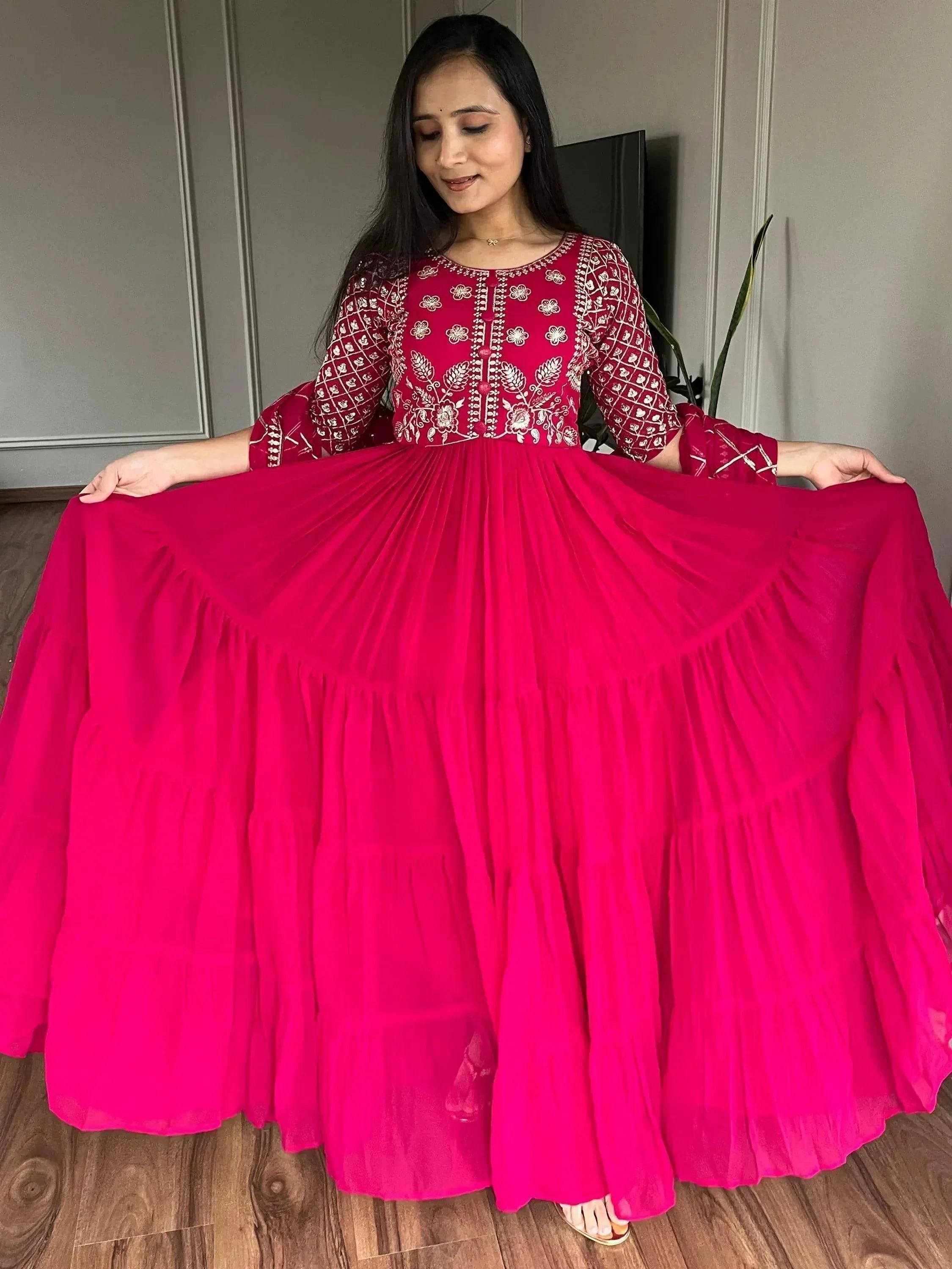 Woman in vibrant pink embroidered ethnic gown with flared skirt, perfect for festive occasions.