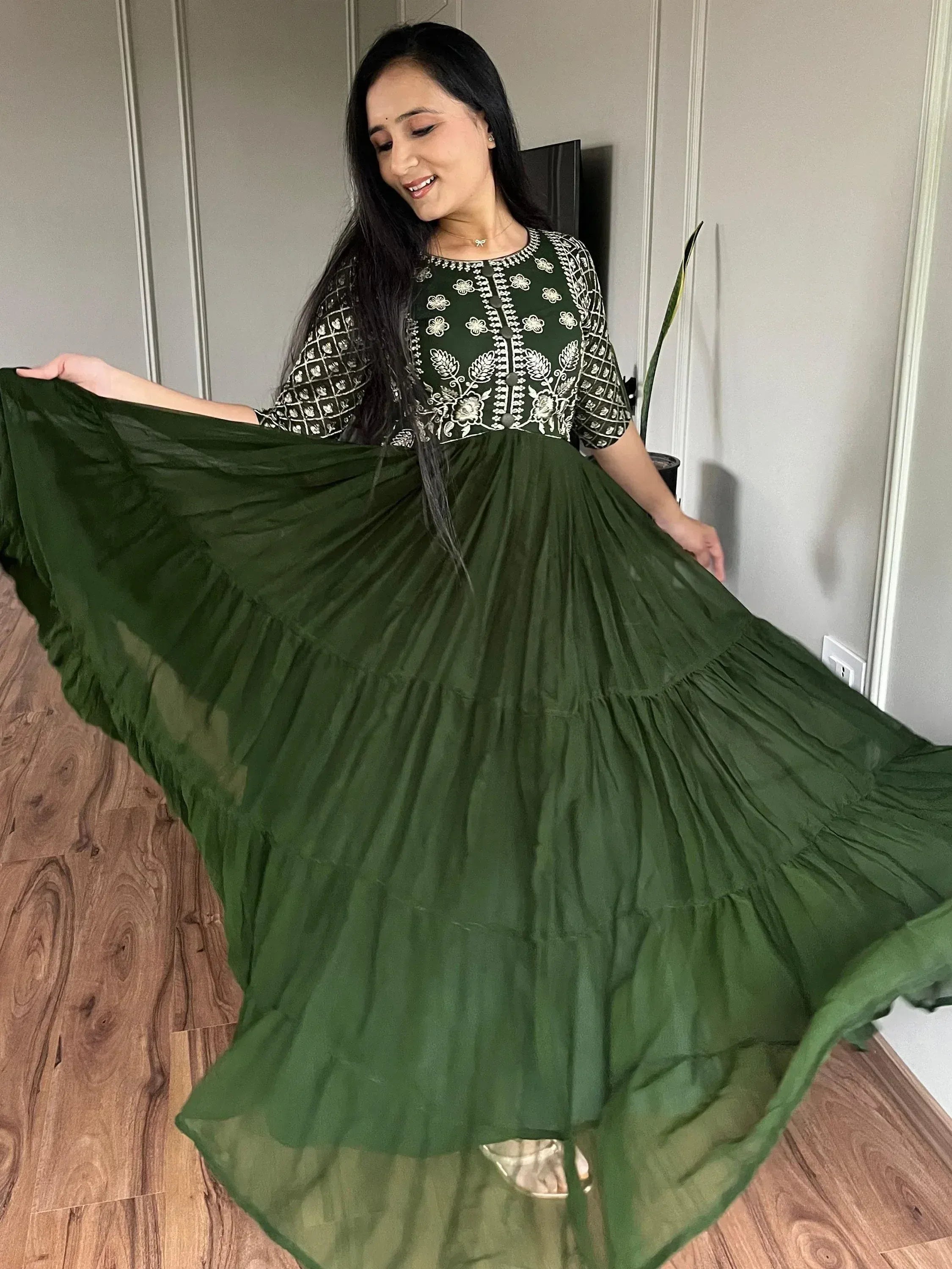 Woman in green embroidered ethnic gown with flared skirt, showcasing designer Indian wear