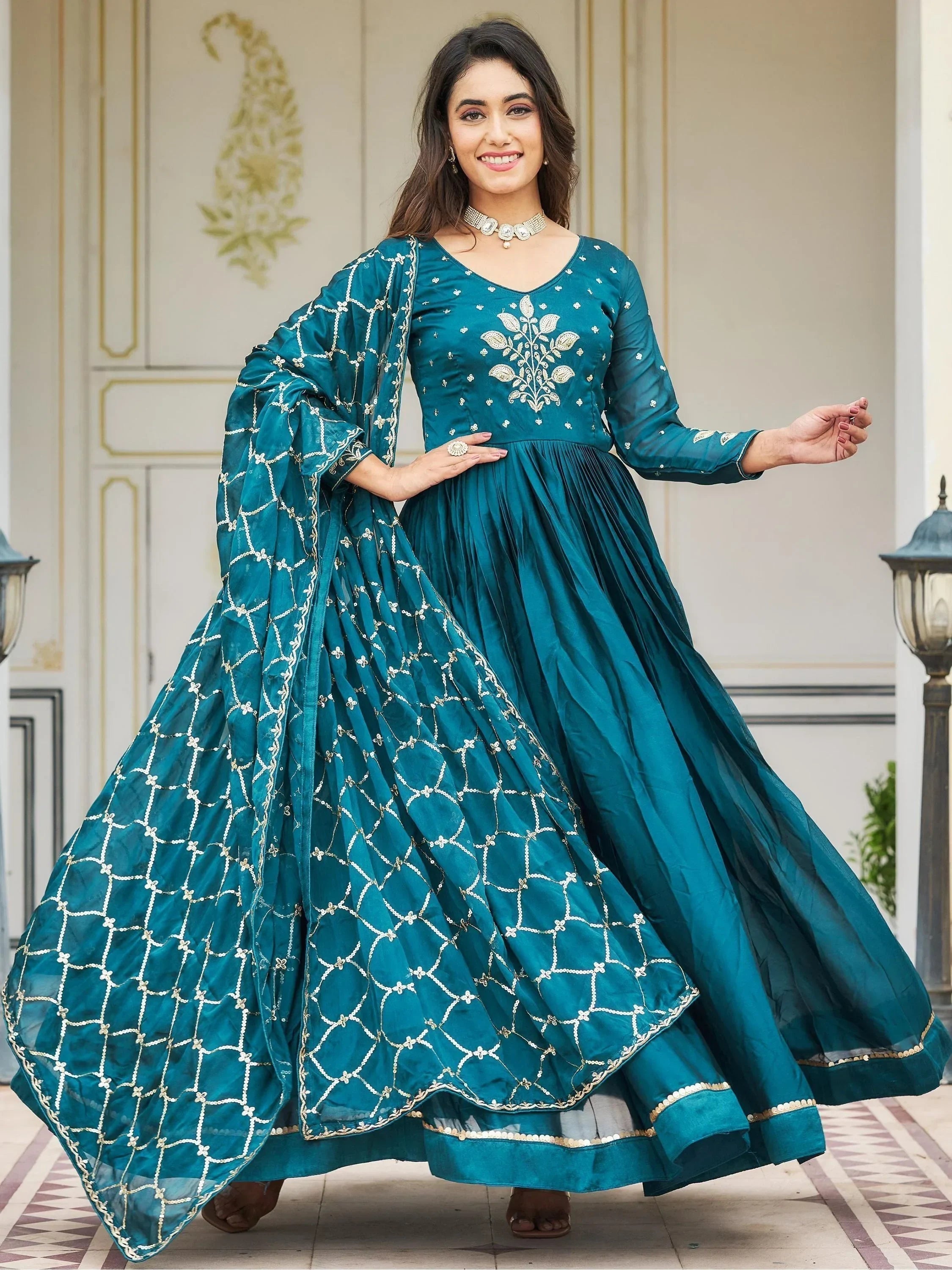 Woman in teal embroidered Anarkali gown with matching dupatta, ideal for Indian ethnic wear.