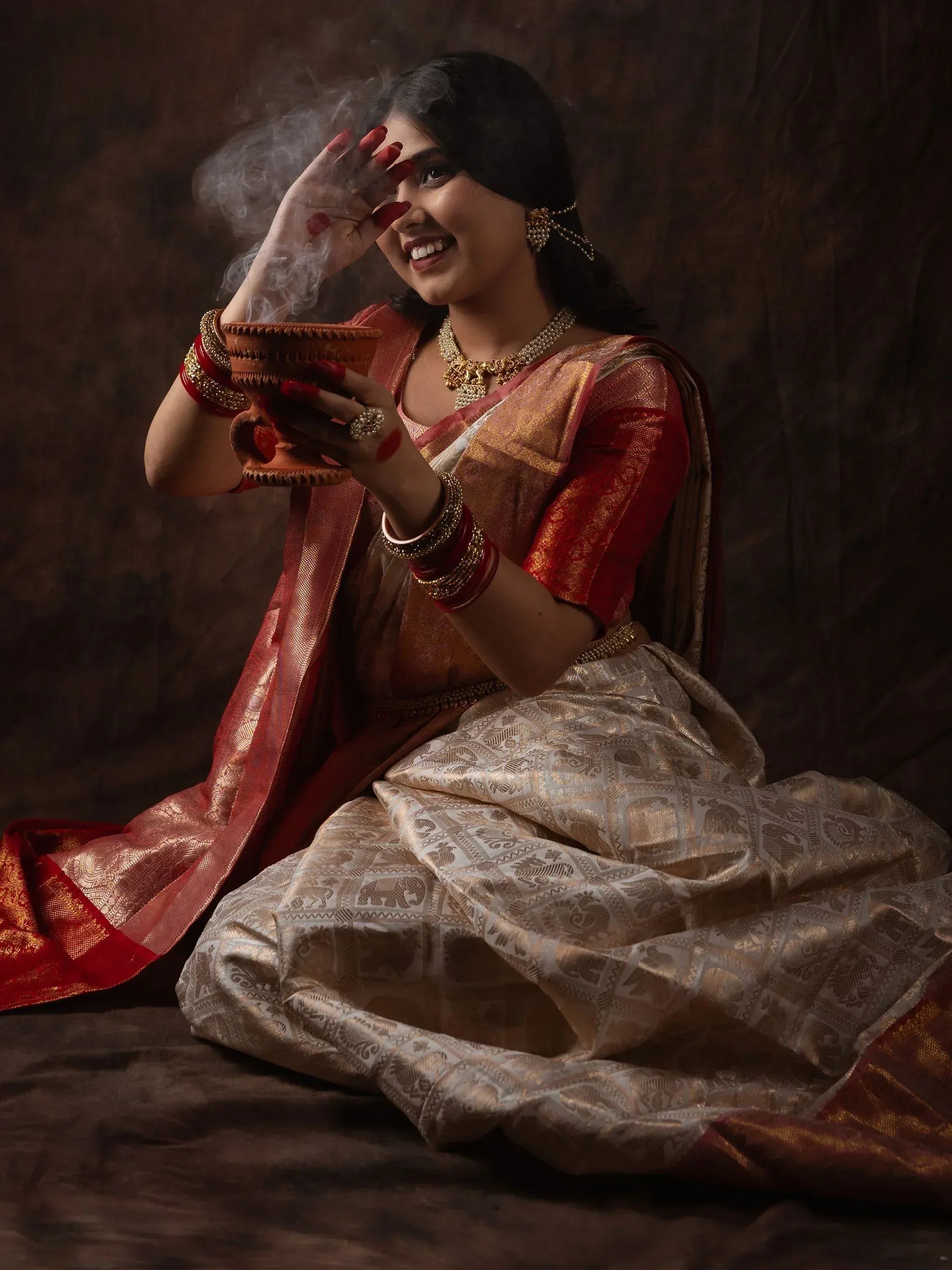 Woman in traditional Indian saree with gold embroidery, holding smoking clay pot, festive ethnic wear