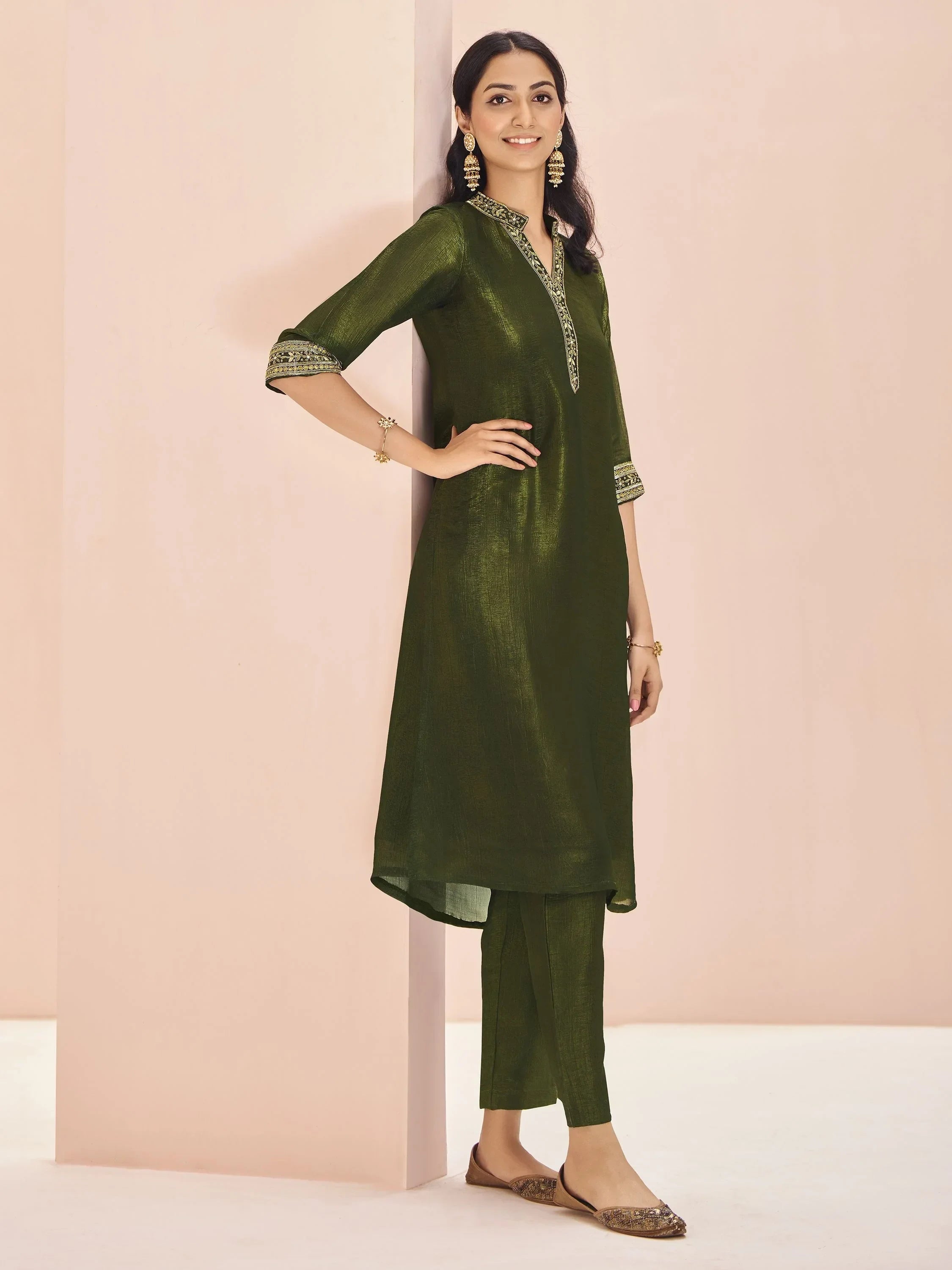 Woman wearing olive green straight cut kurti with matching pants and ethnic earrings