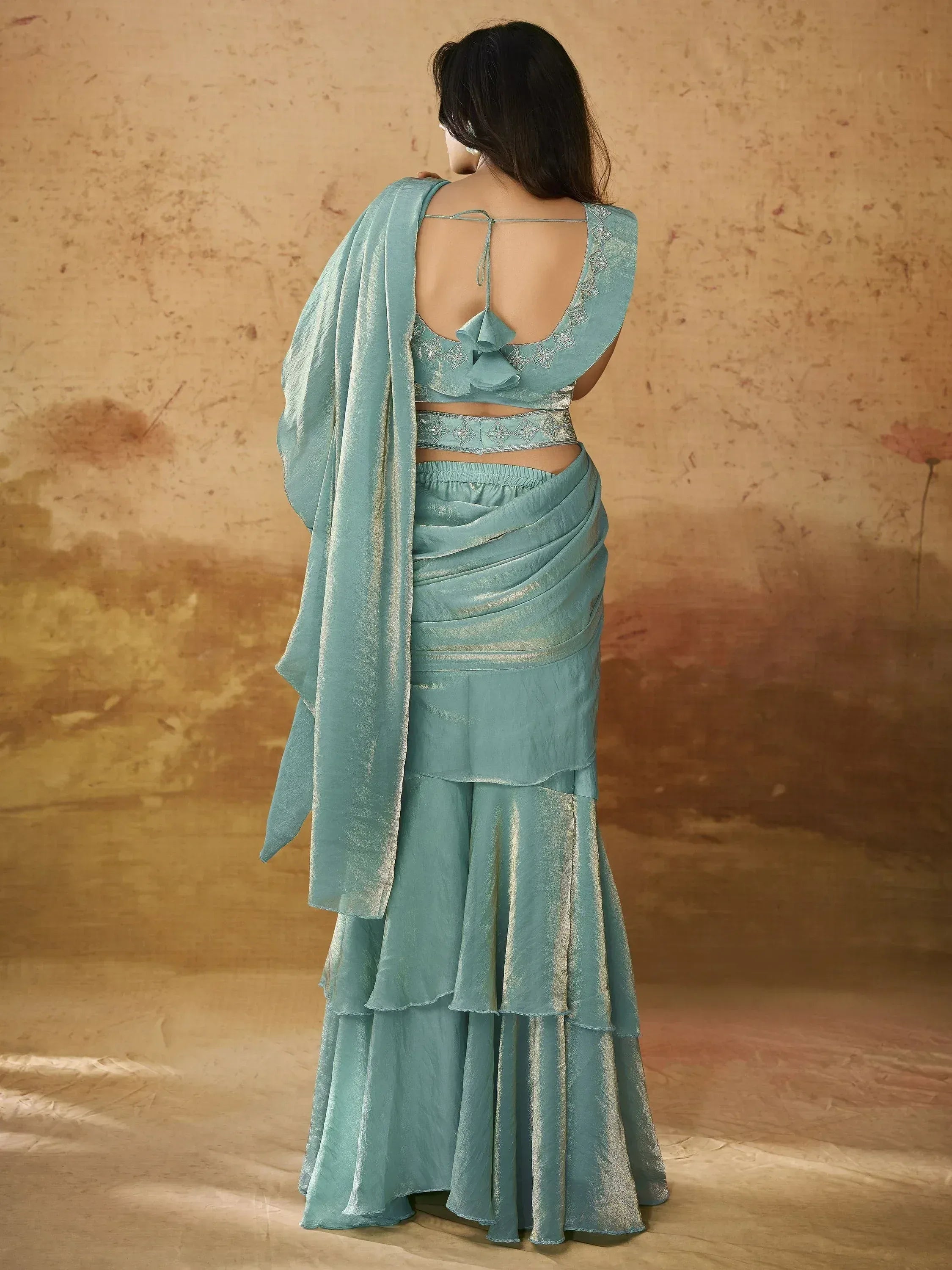 Back view of woman in light blue designer lehenga choli with ruffled skirt and embroidered blouse