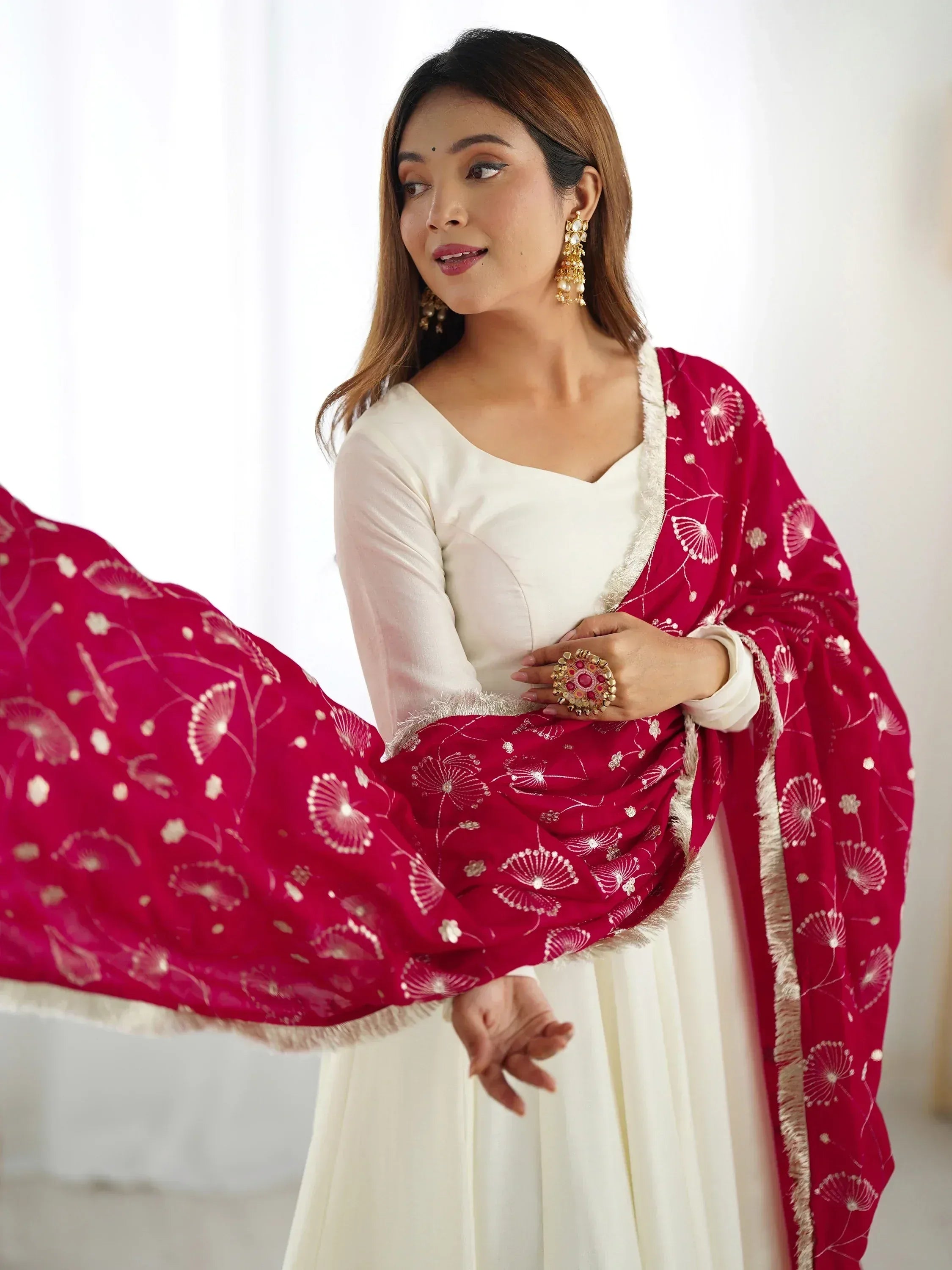 Woman in white ethnic gown with pink embroidered dupatta and gold earrings