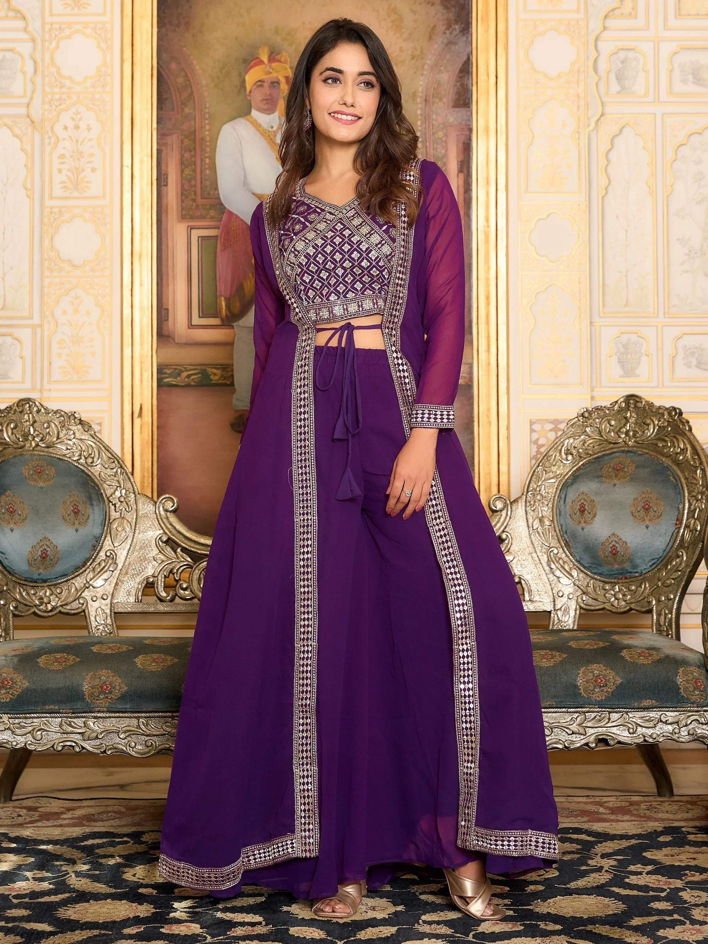 Woman wearing a purple embroidered lehenga choli with sheer long jacket, standing indoors
