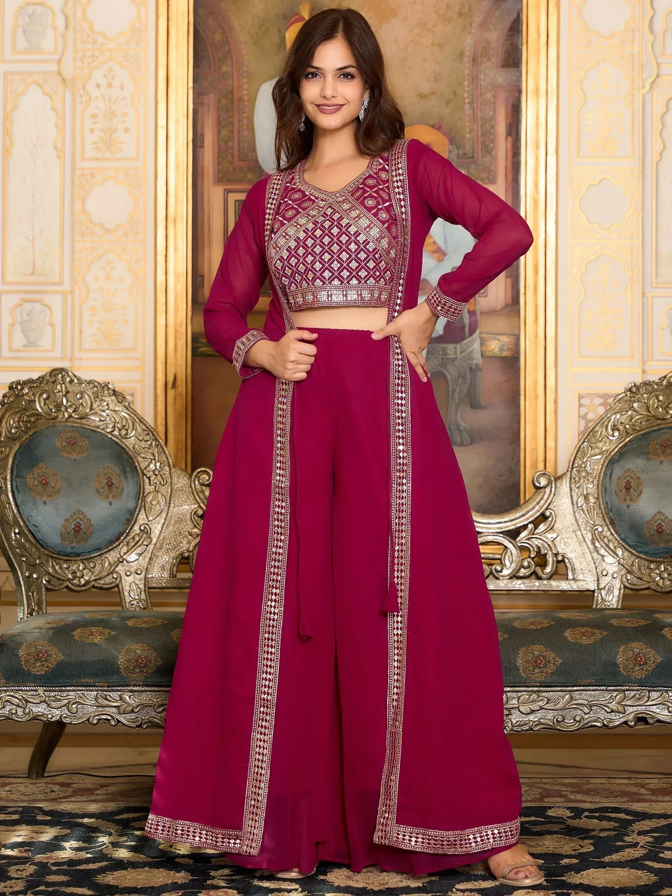 Woman wearing a magenta embroidered palazzo suit set with dupatta in ornate room