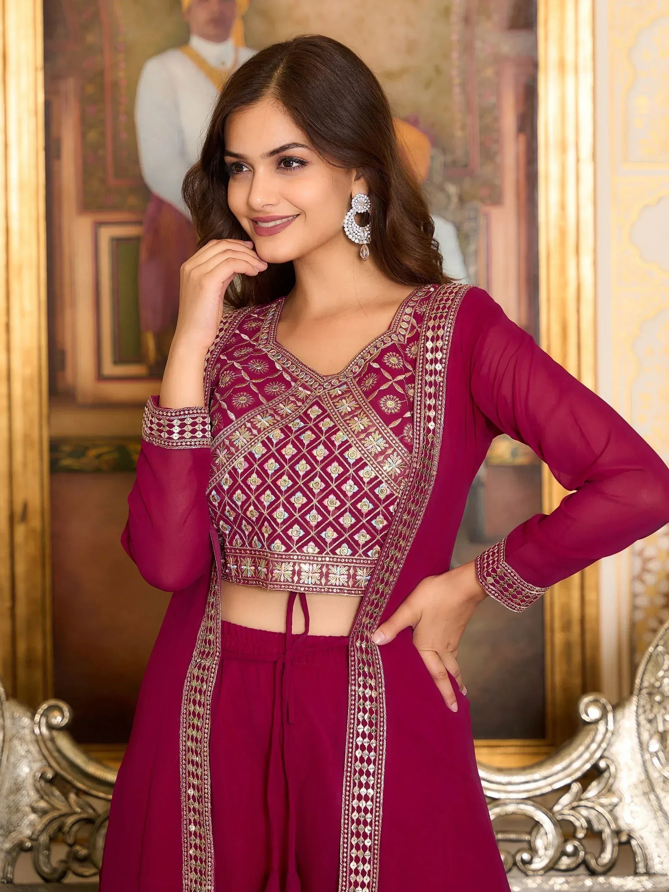 Woman in magenta embroidered ethnic outfit with statement earrings, traditional background