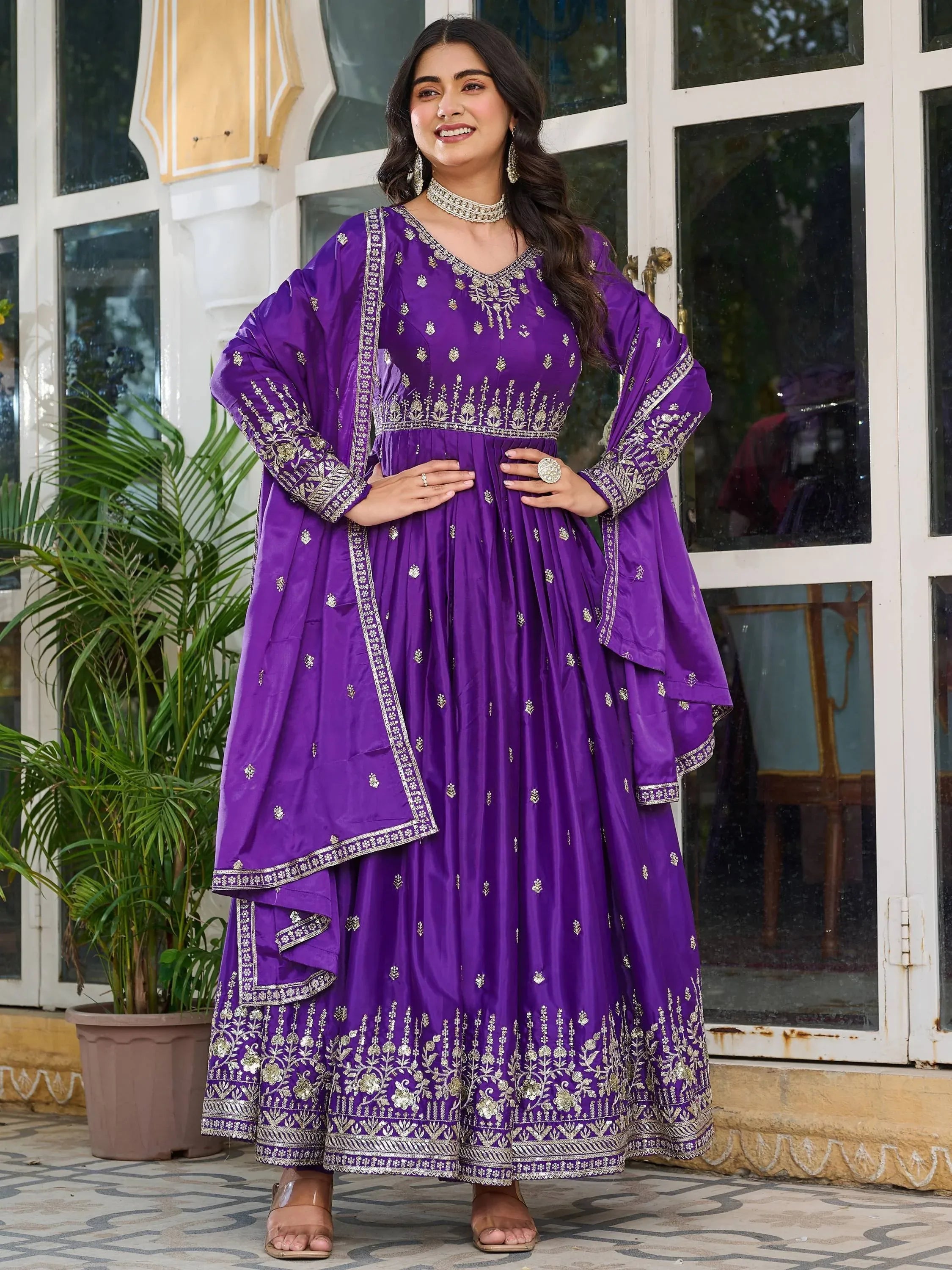 Woman wearing a purple embroidered ethnic gown with dupatta, standing outdoors