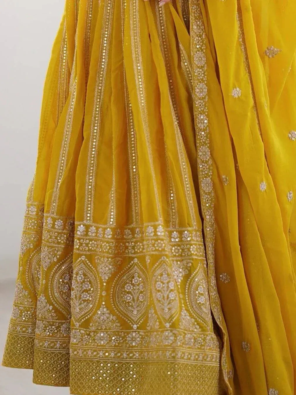 Yellow velvet lehenga choli with intricate gold embroidery and mirror work, perfect for Indian ethnic wear.
