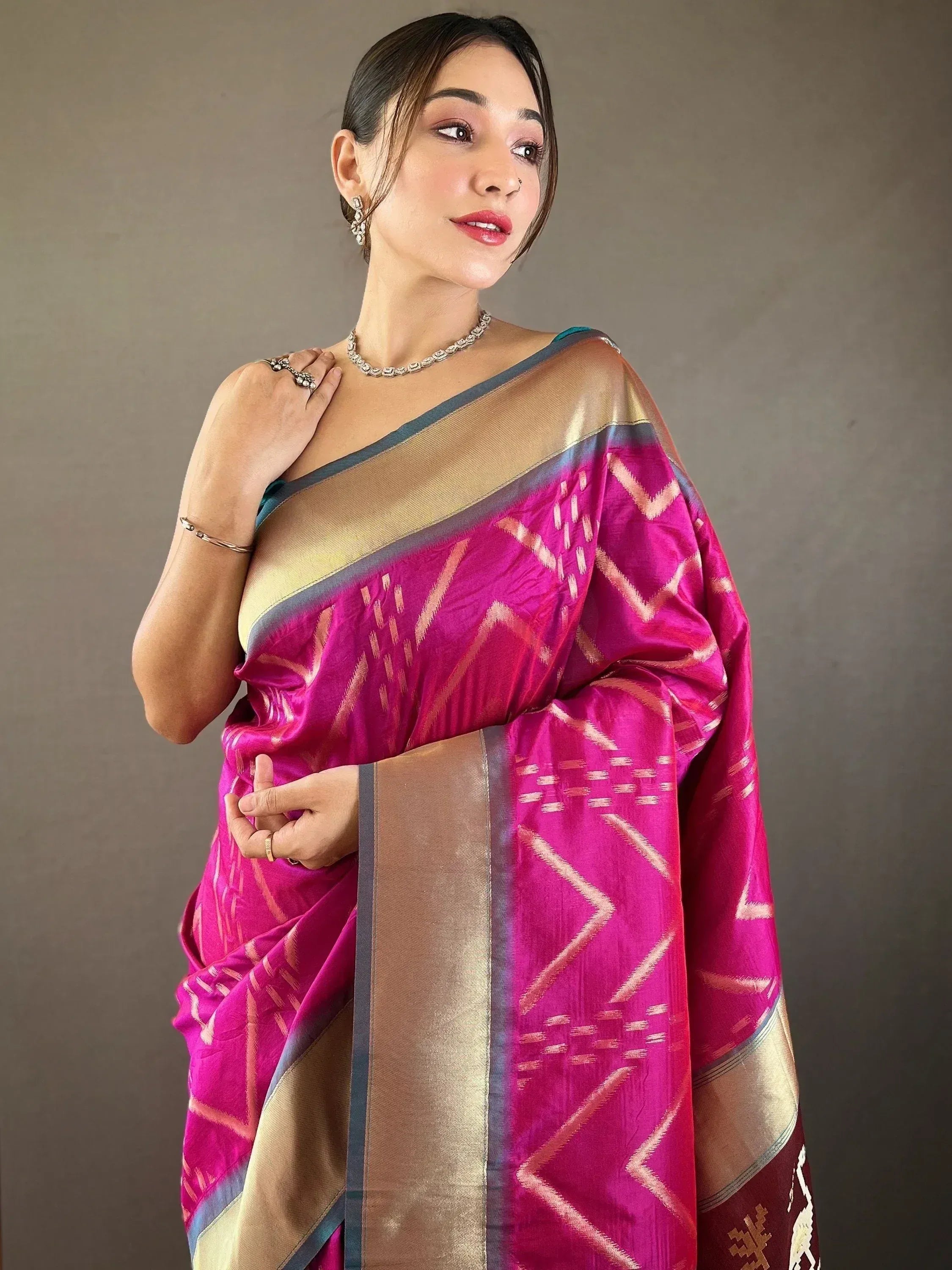 Vibrant pink ethnic saree with gold geometric patterns and border, styled with traditional jewelry