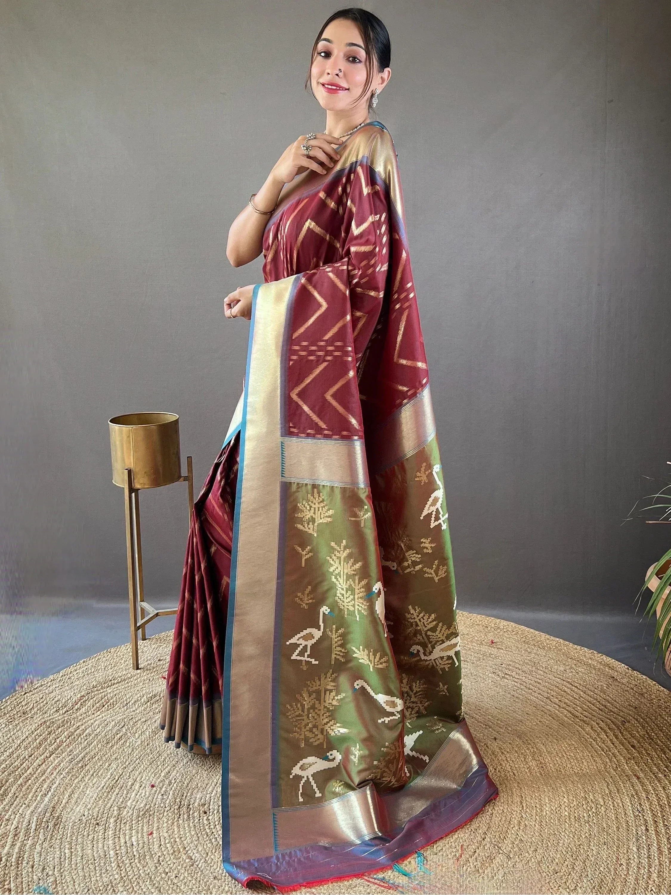 Woman in maroon and green designer saree with geometric and bird motifs, ethnic Indian wear